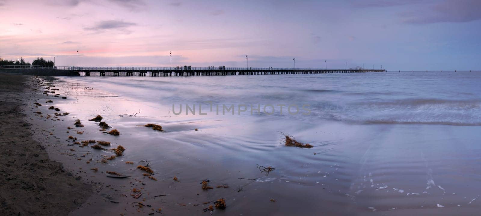 The sunset light is fading over the long pier