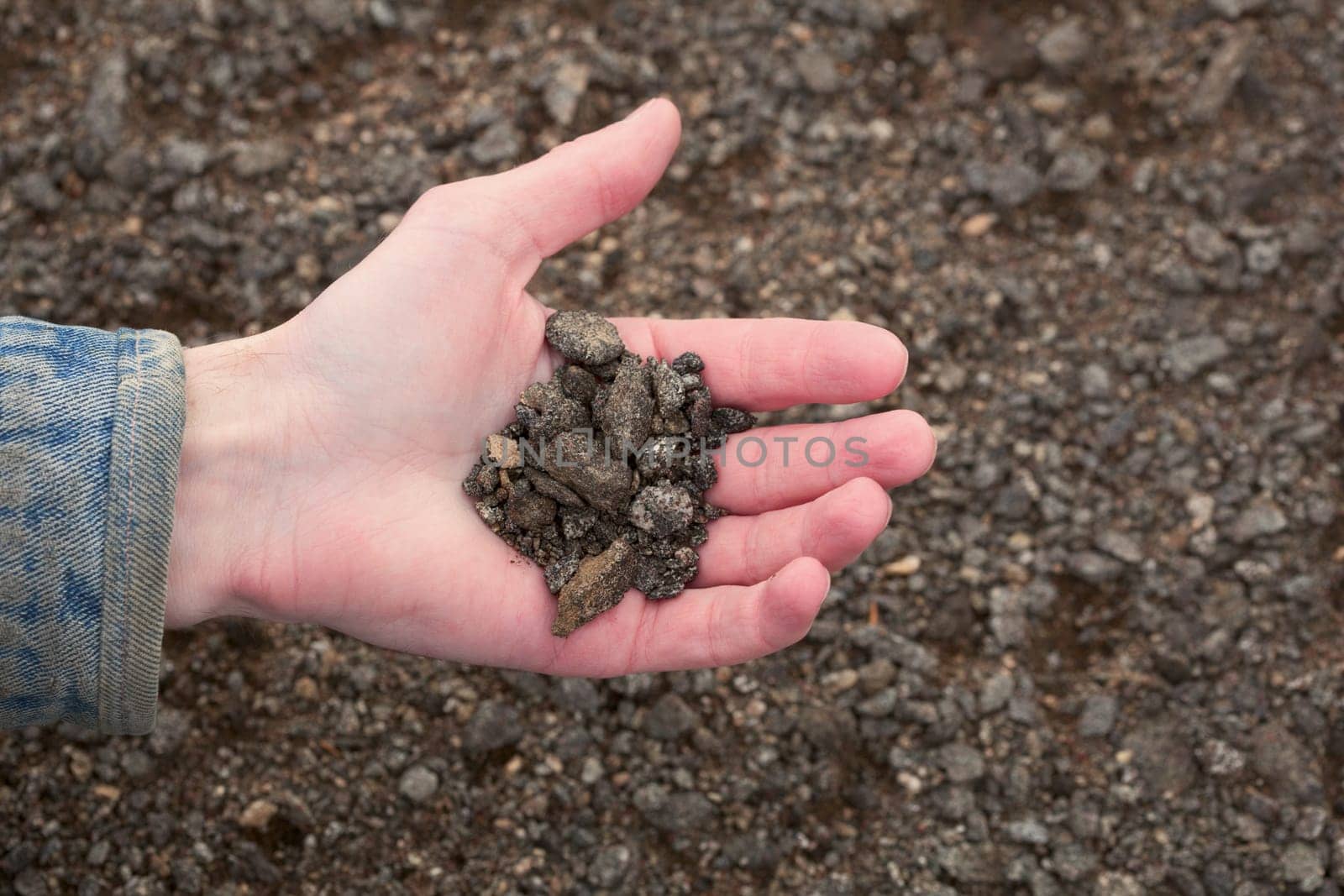 Hand of the farmer holding handful of the infertile earth