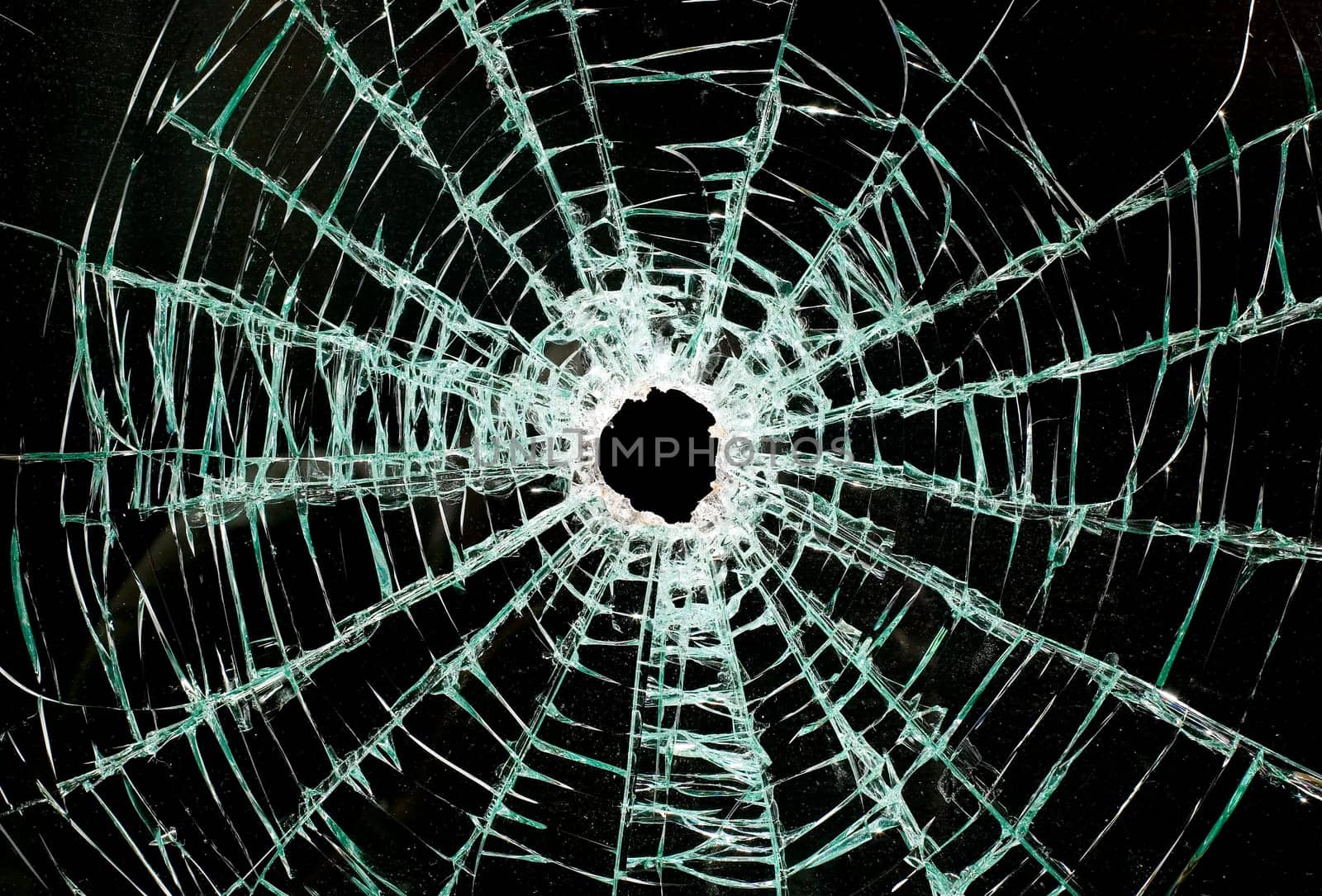 There is a broken car glass of windscreen with hole in picture center, looks like black space