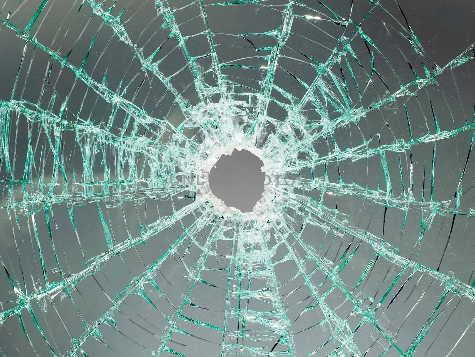 There is a broken car glass of windscreen with hole in picture center
