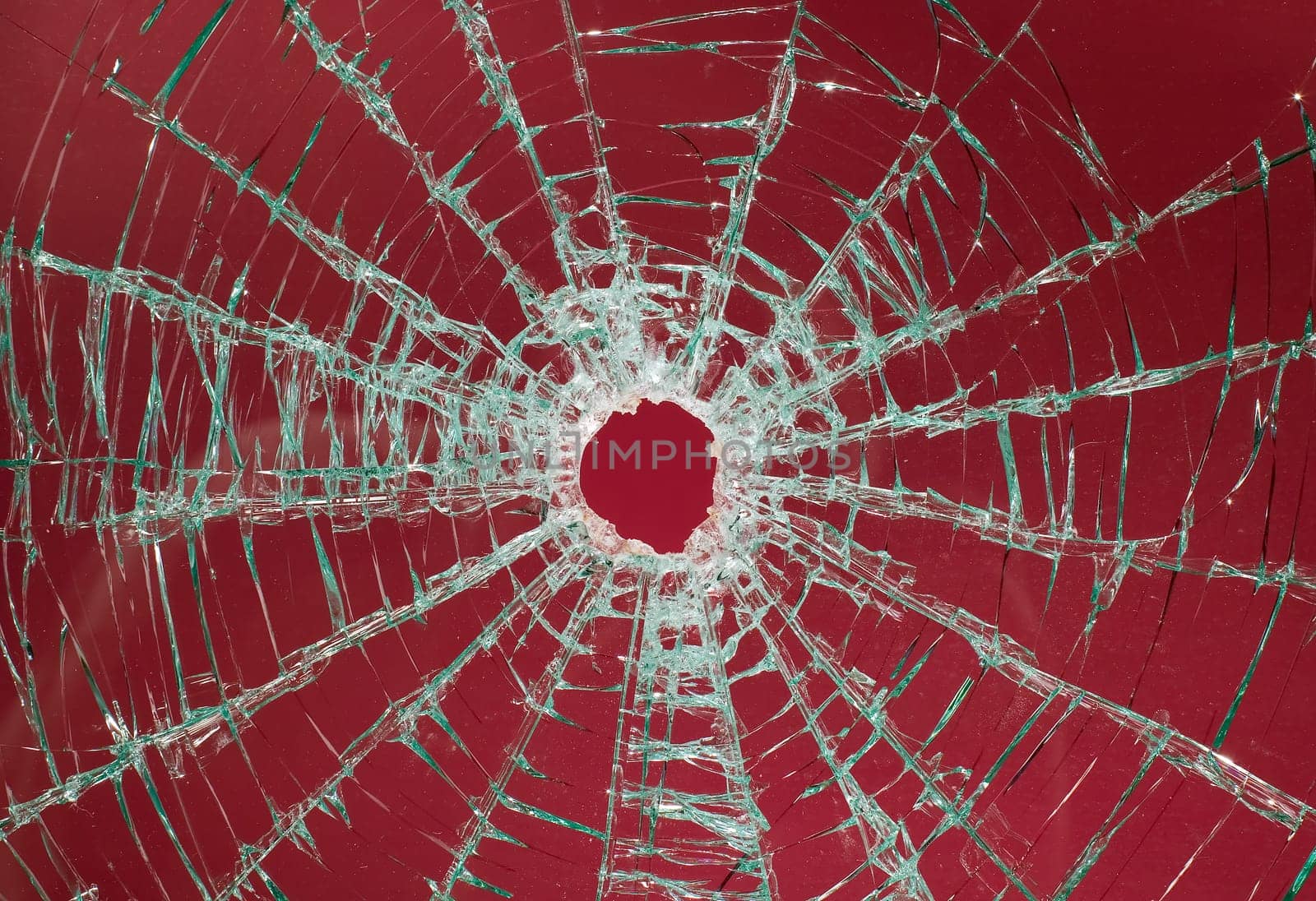 There is a broken car glass of windscreen with hole in picture center