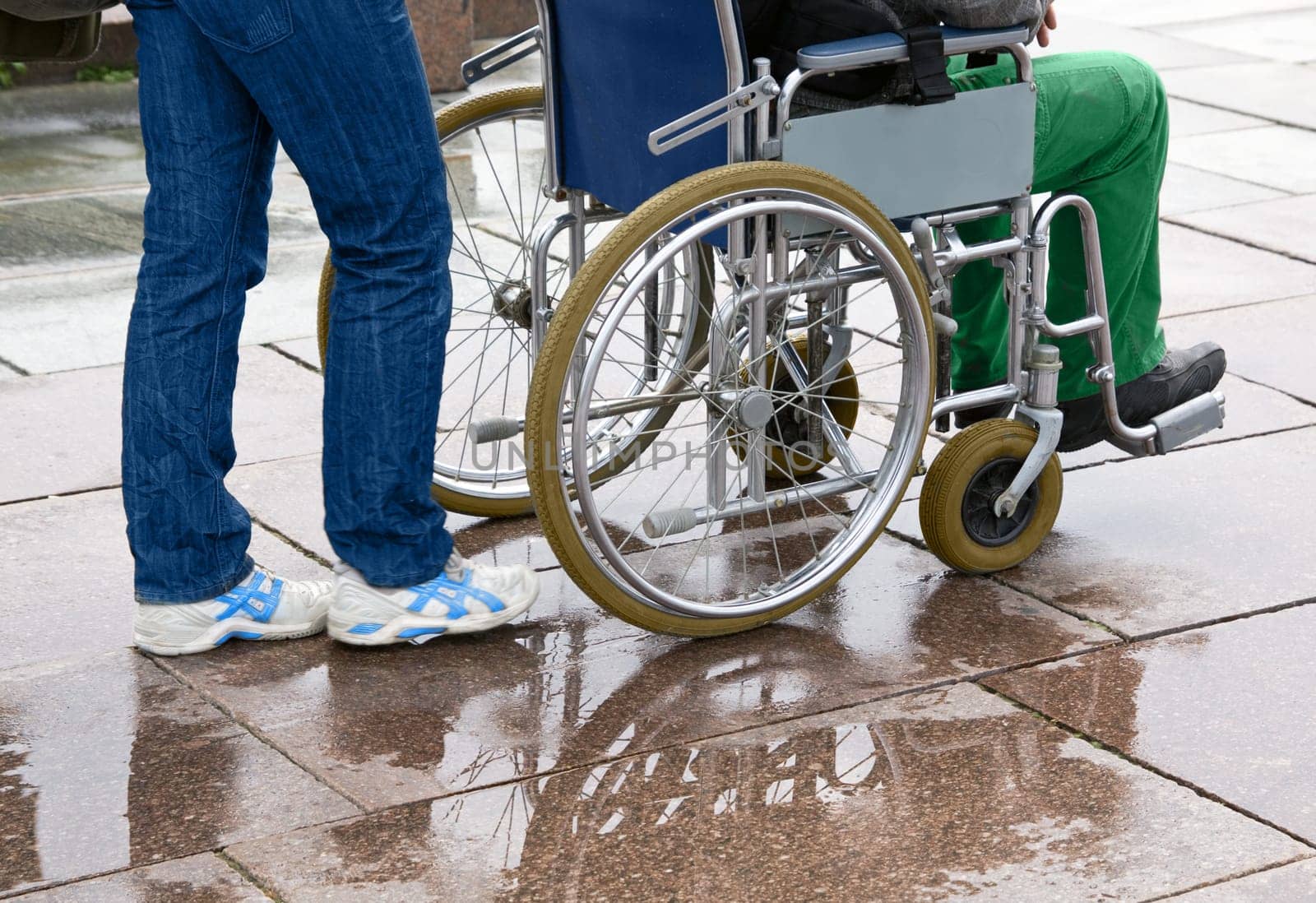Woman pushing man in wheelchair along street