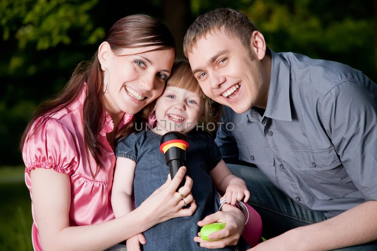 Family Lifestyle Portrait Of A Mum And Dad With Their Kid Having Fun Outdoors
