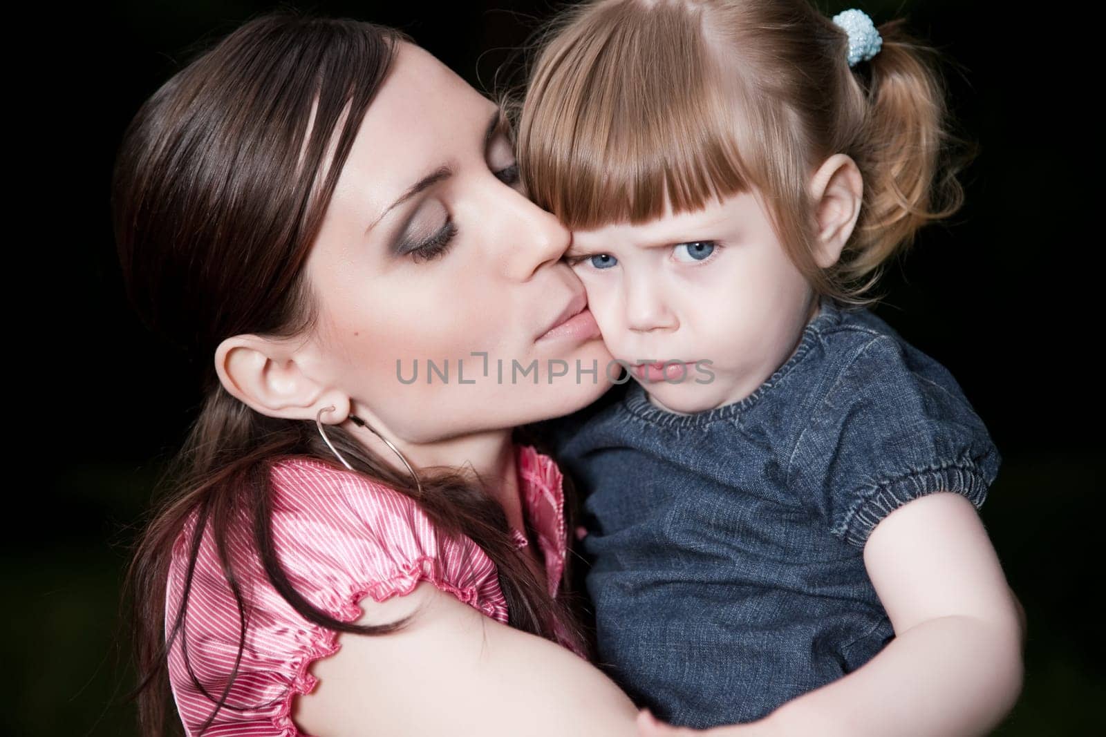 Mother Kissing Daughter Cheek. Close-Up Portrait