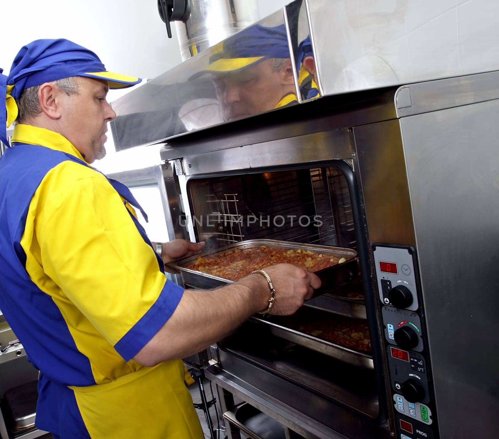 a cook inserts a dish in the oven