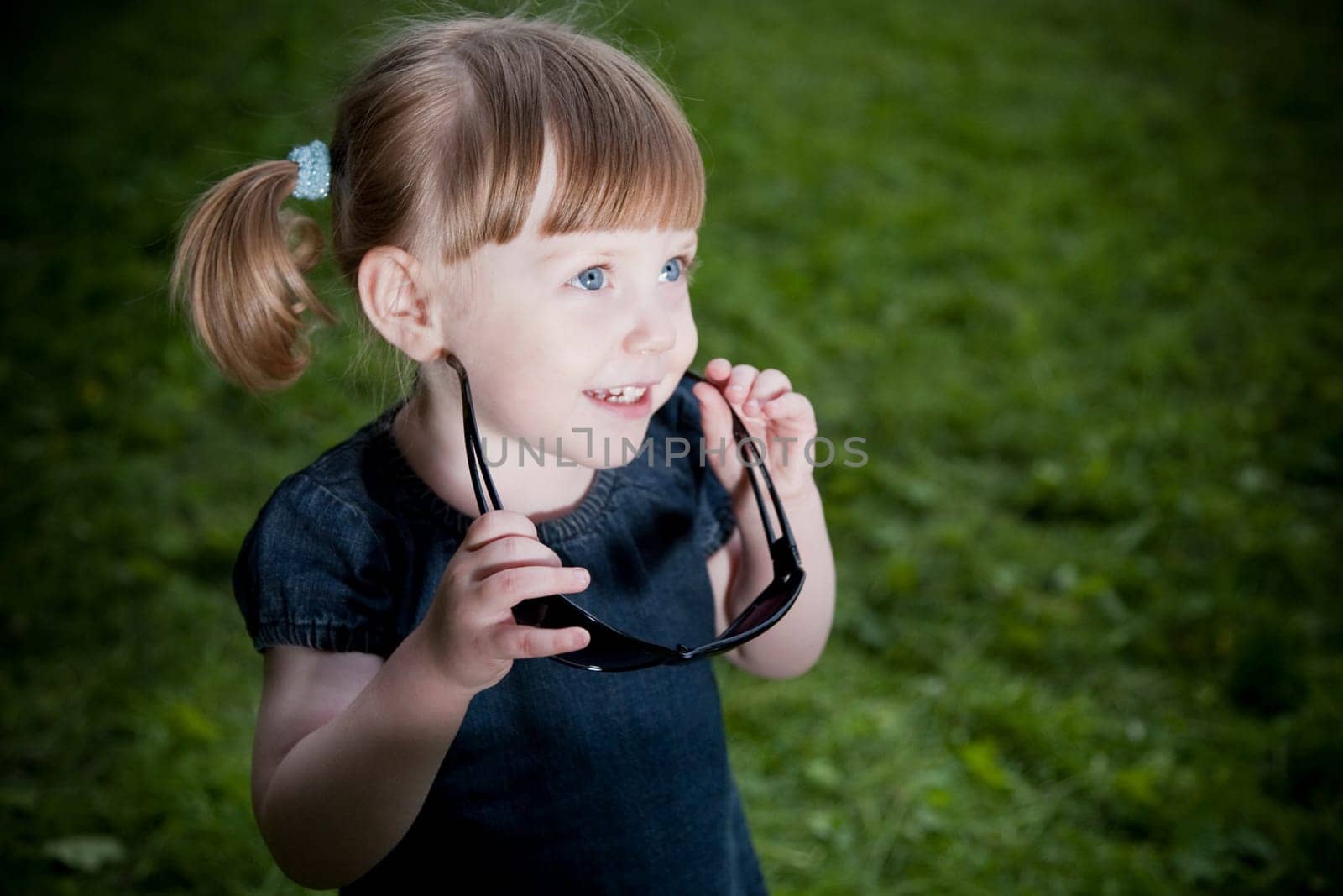 Little Girl With Sunglasses On The Nature Background