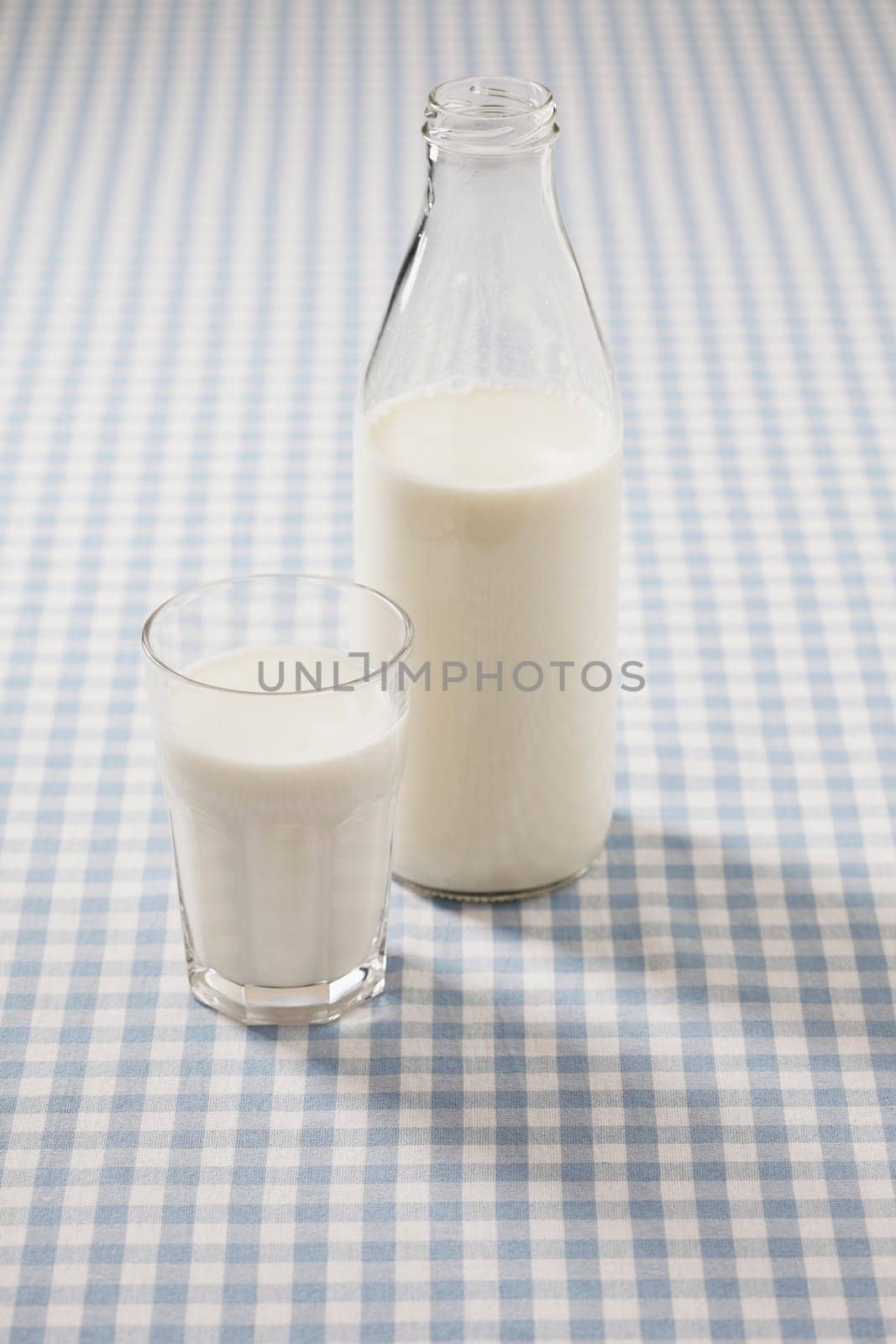 Milk in a glass and a bottle on a plaid tablecloth