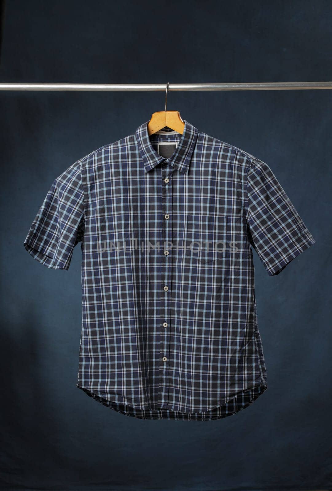 A new men's blue plaid cotton shirt hanging on a hanger.
