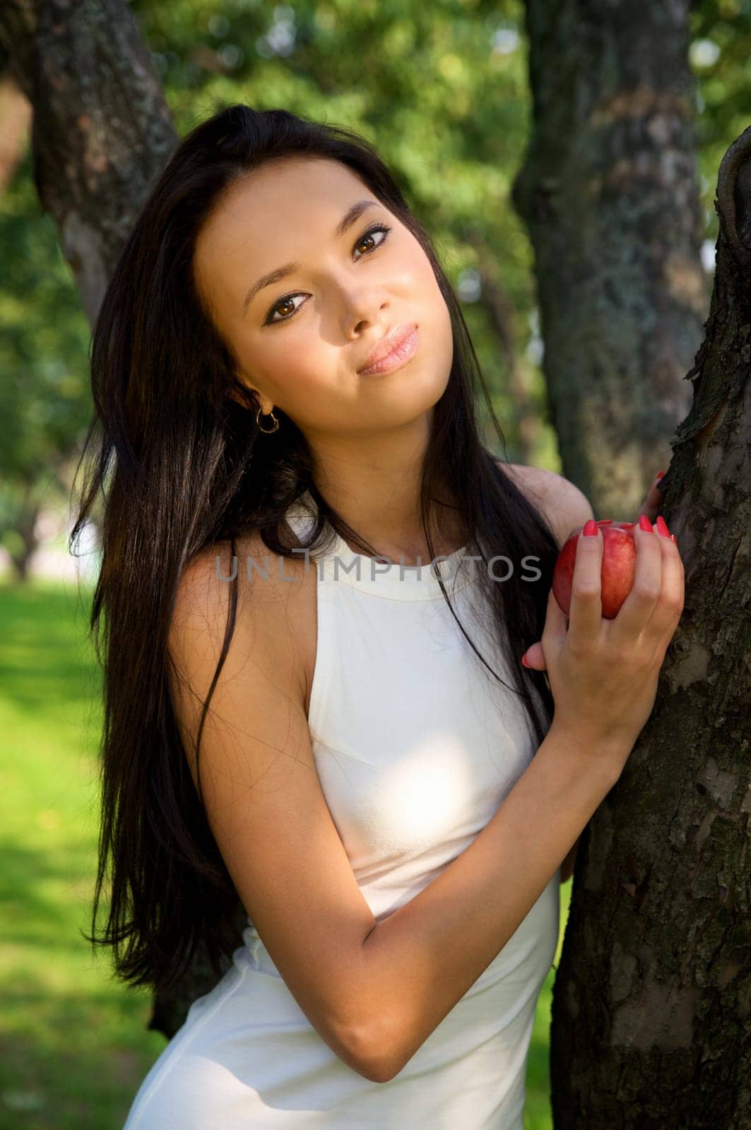 Beautiful young women holding a red apple in the garden