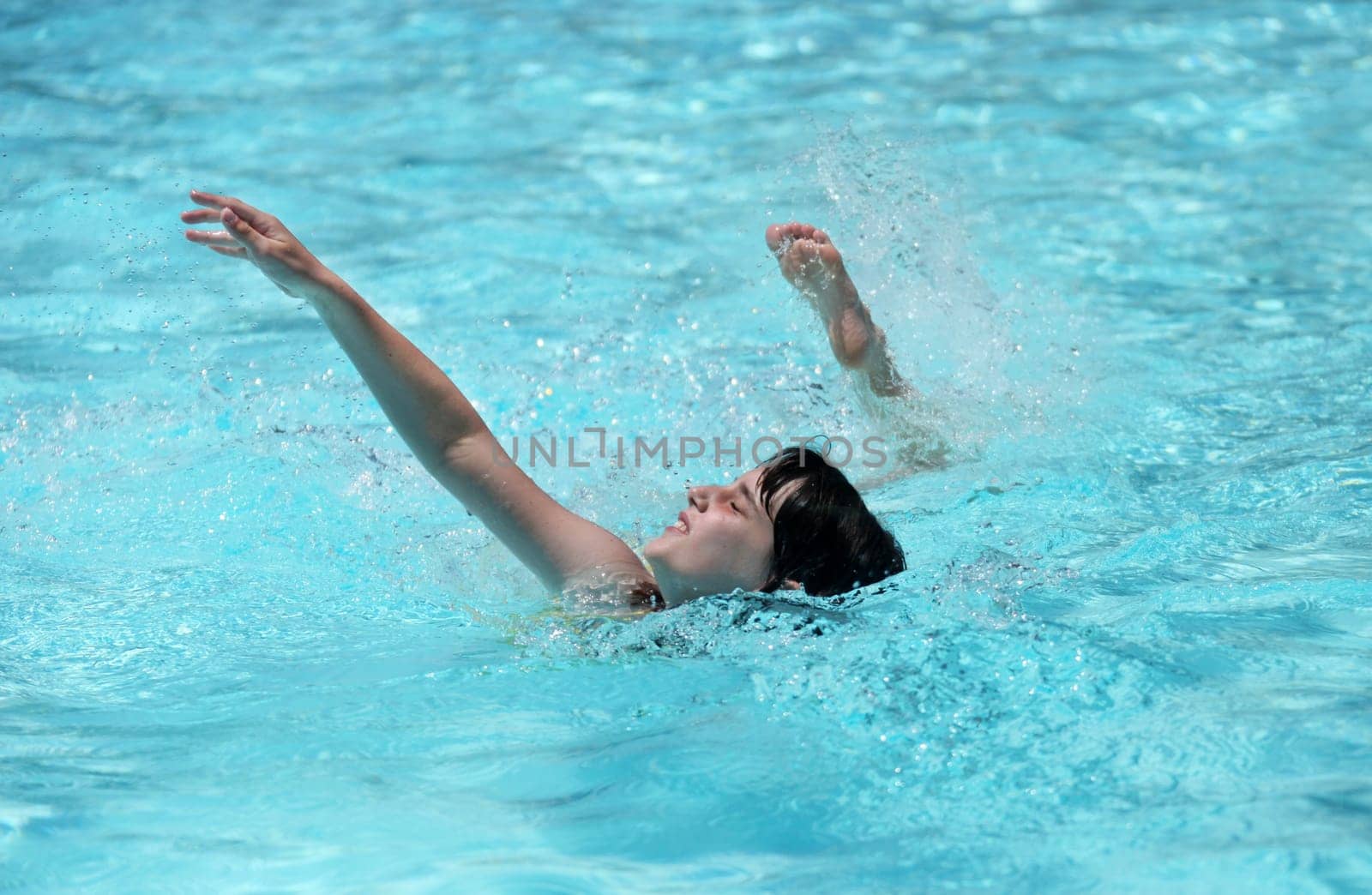Child Swimming in a Pool With Arm and Leg Out in Mid Stroke