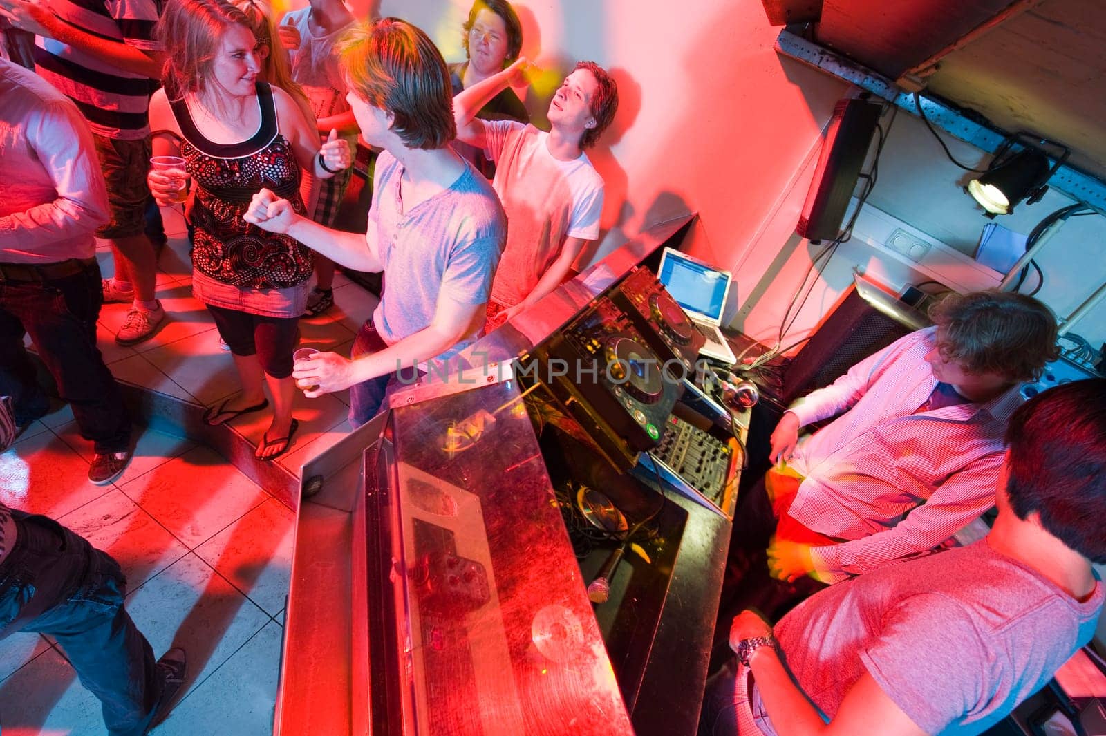 People dancing and flirting near the DJ booth at a nightclub