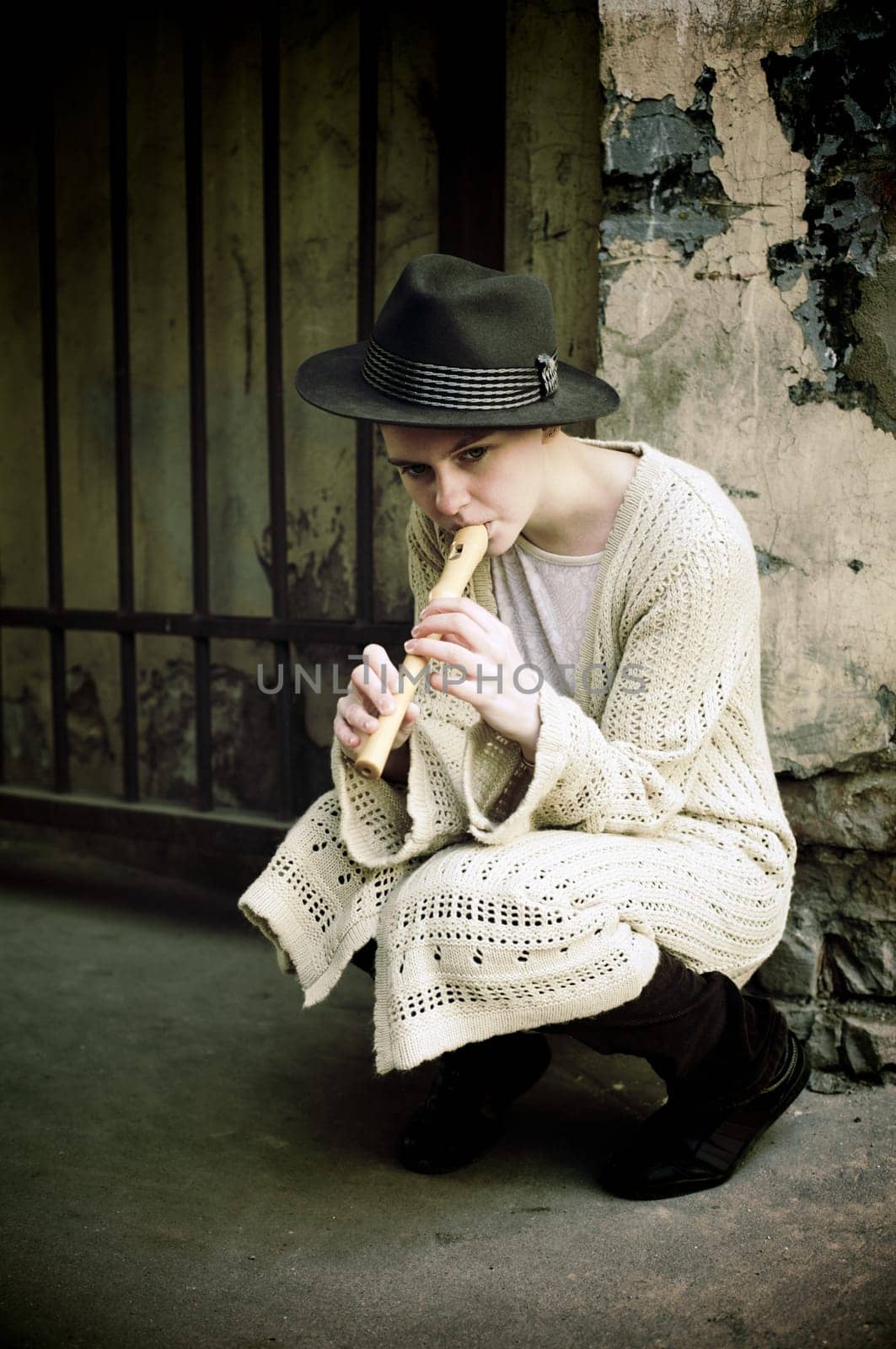 Young girl in a hat playing flute on the street