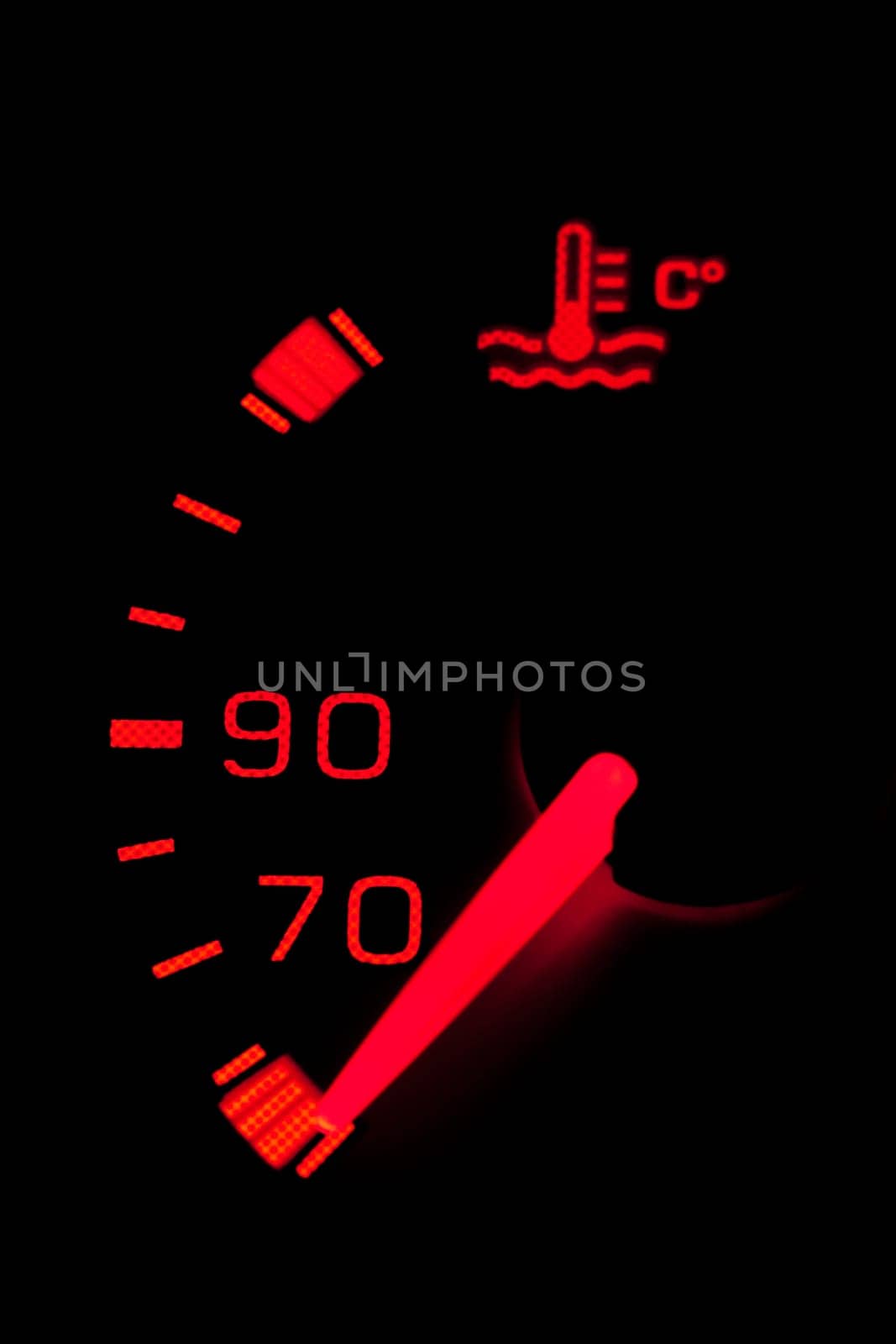 Car dashboard gauges illuminated over a black background. Shallow depth of field