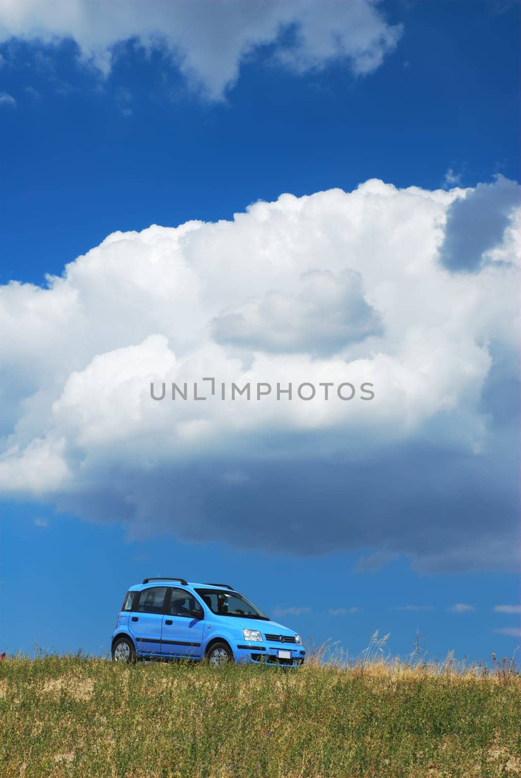Bright pale blue modern car under white cloud and blue sky