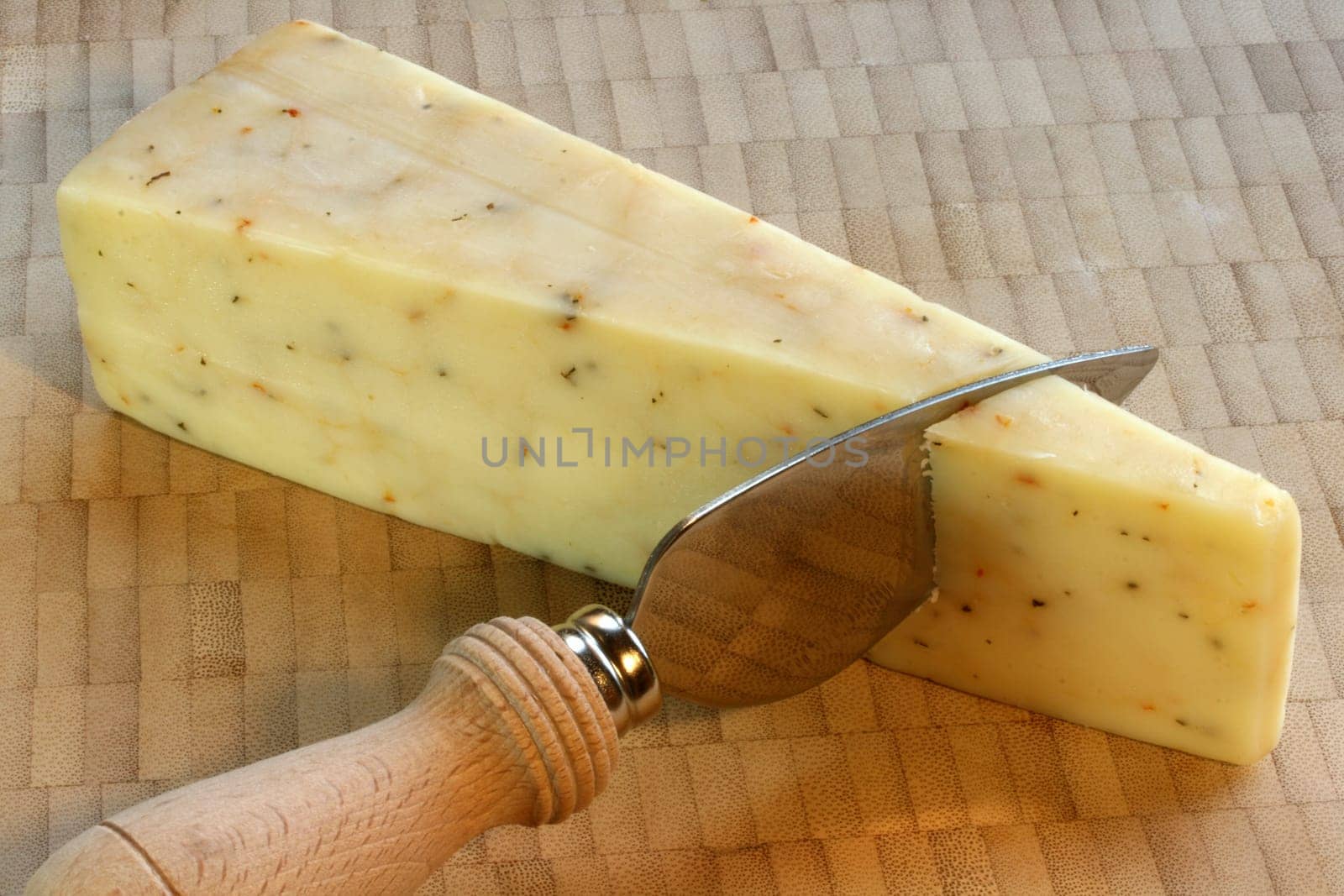 white cheddar cheese with basil and tomato on bamboo cutting board with knife
