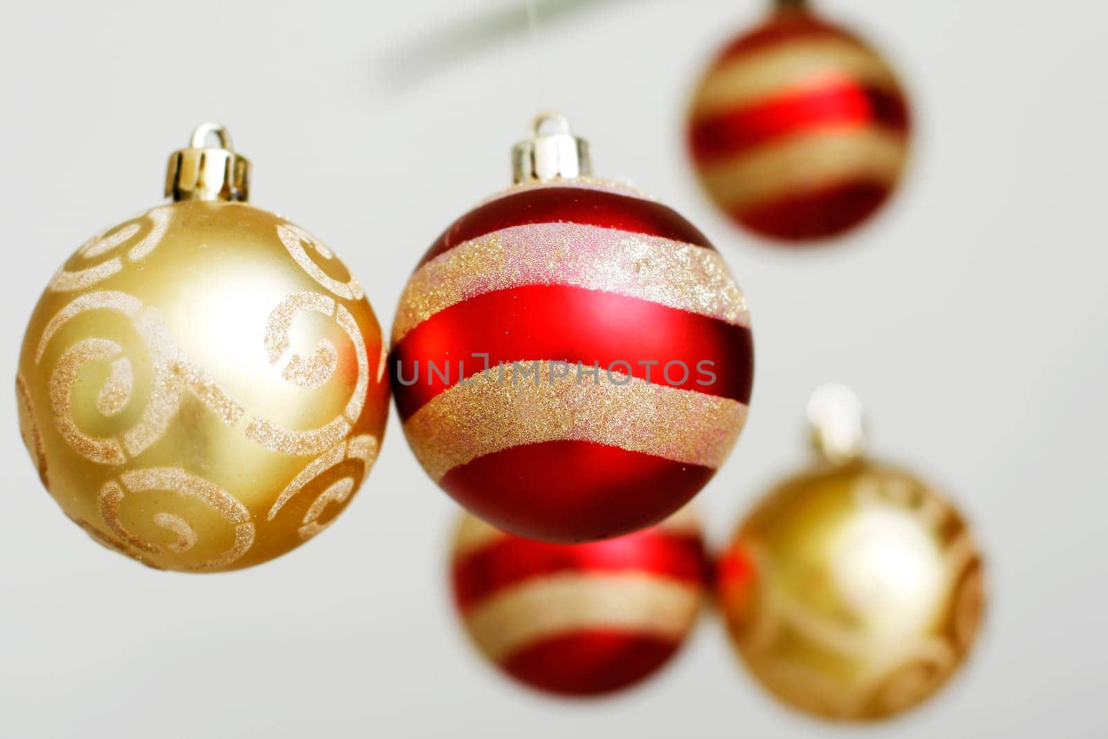 A close-up of red and gold colored decorative Christmas baubles hanging down.