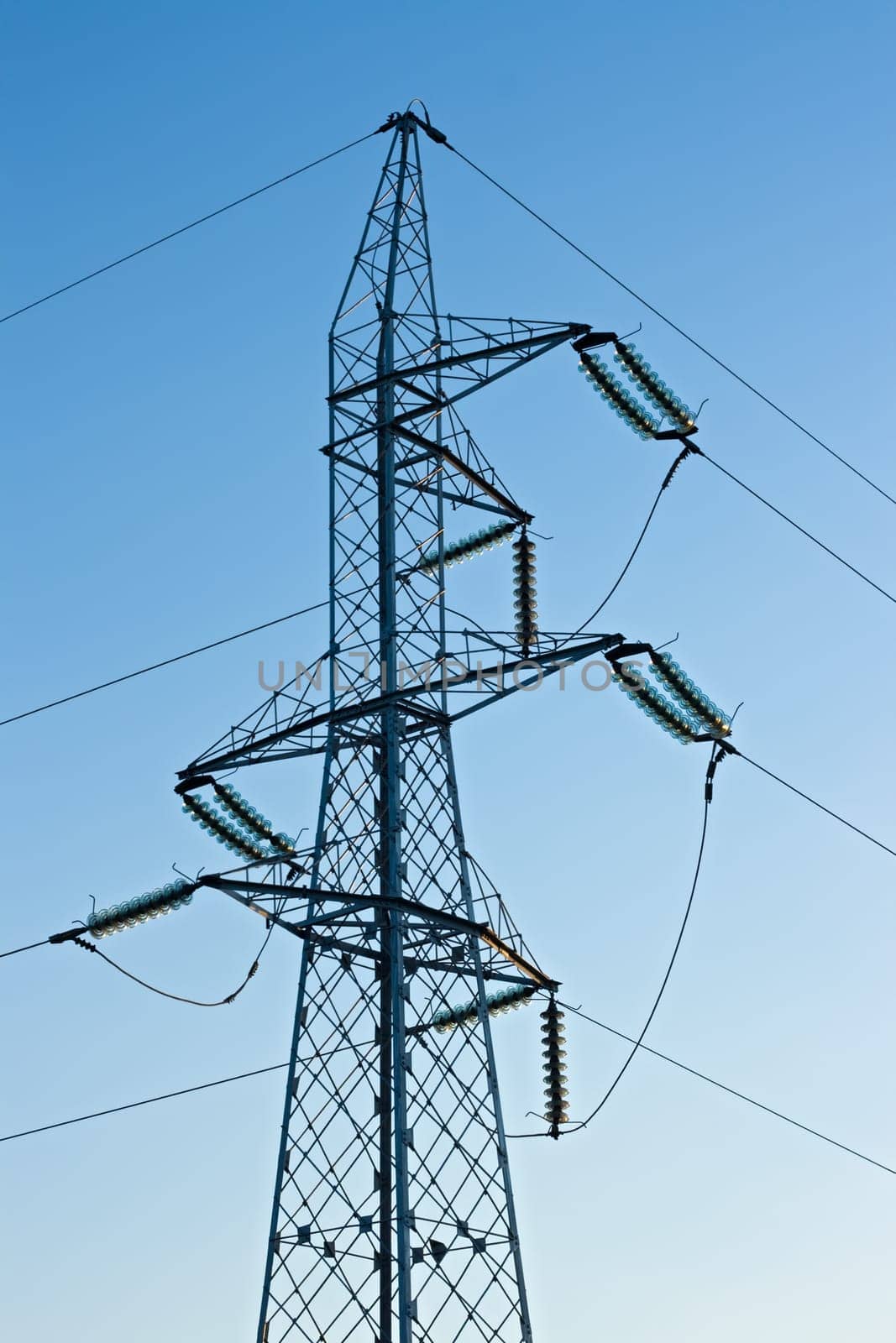 High voltage pylon with cables on blue sky background