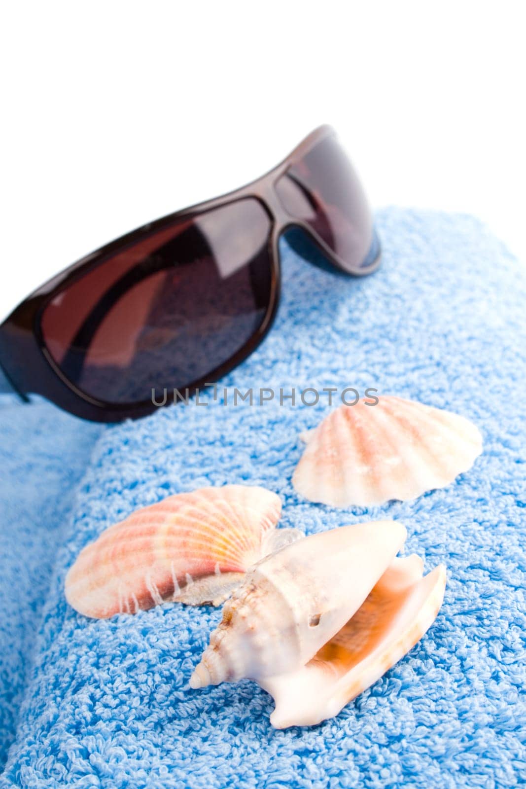 towel, shells, sunglasses closeup on white background