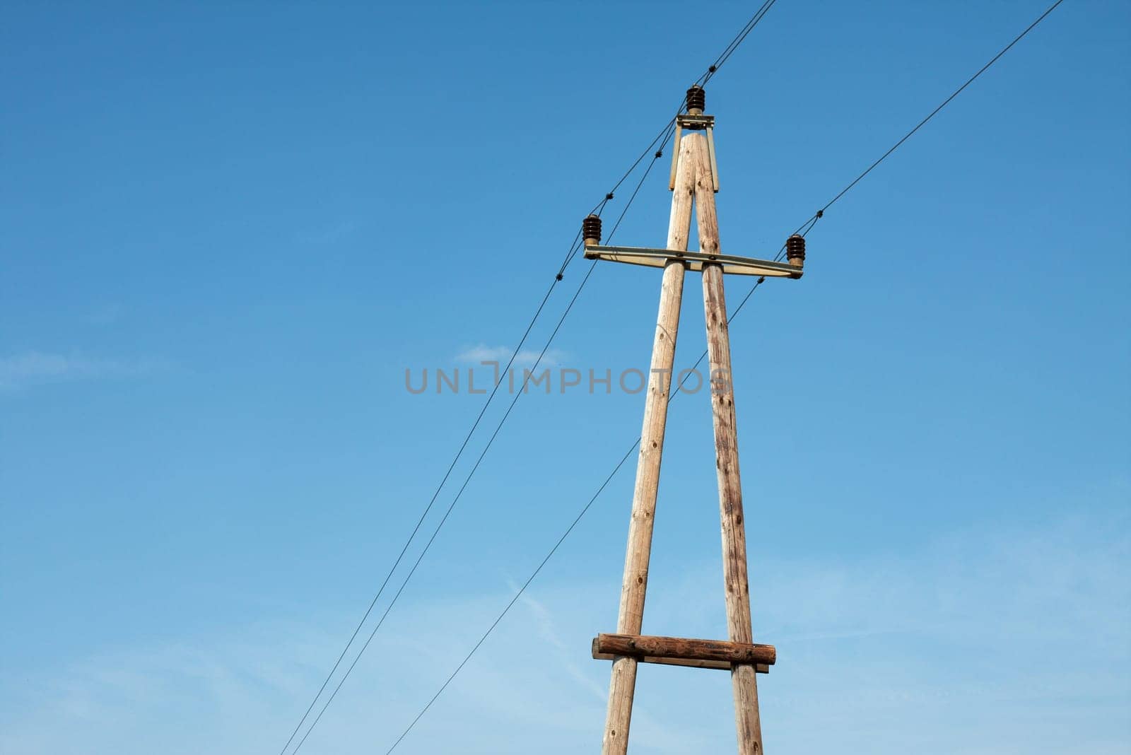 Old wooden electric pillar against blue sky