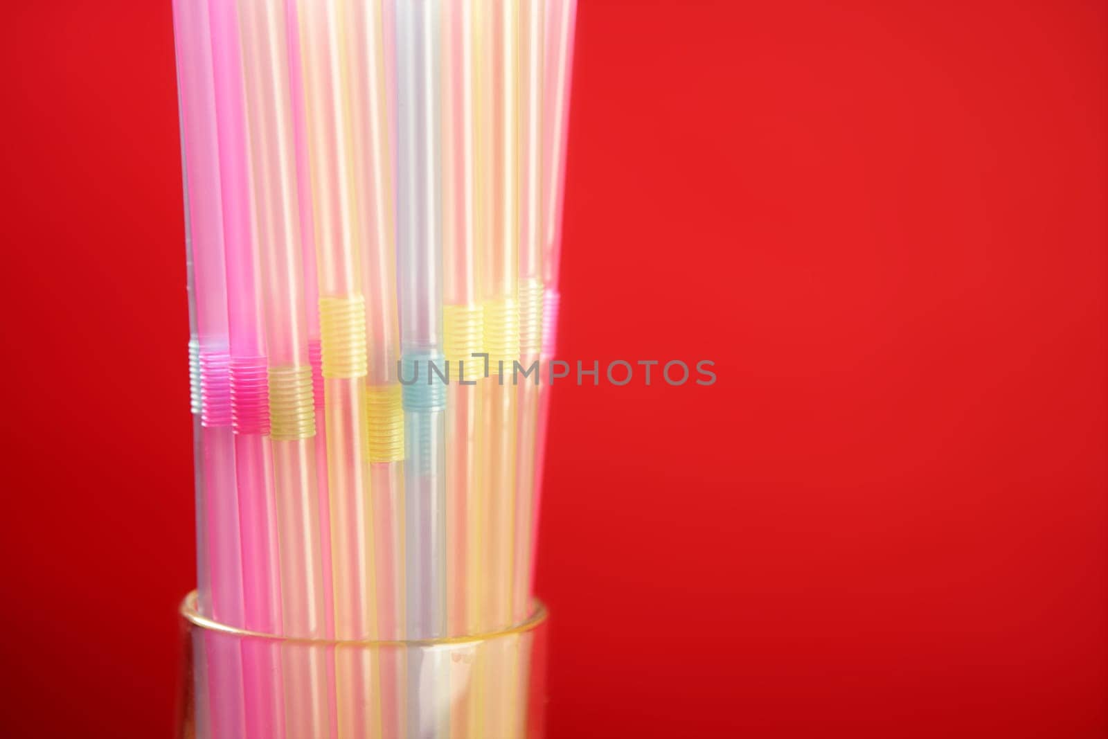 Colorful plastic drink straw over red copy space background