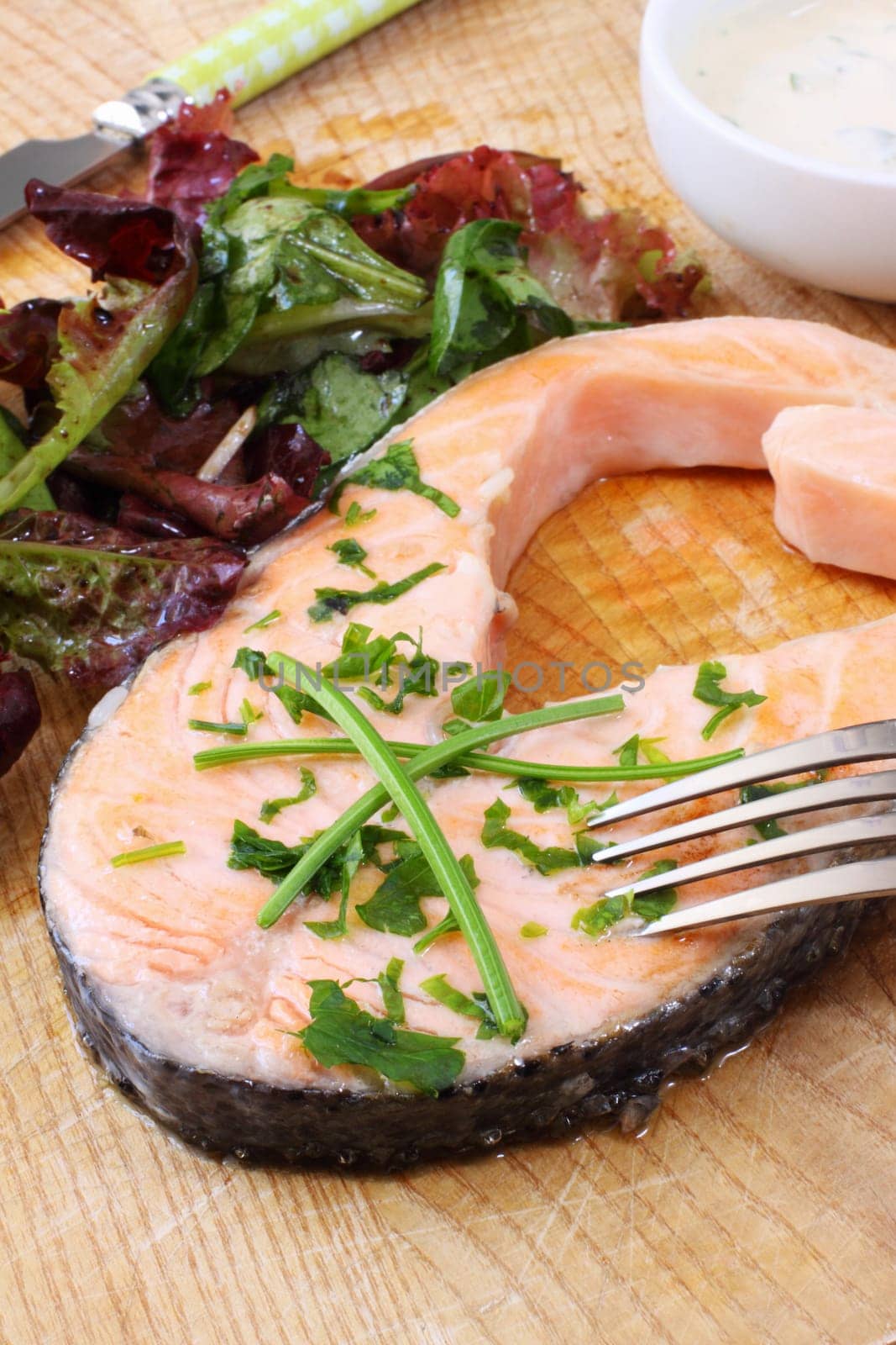 grilled salmon steak on wooden board with salad
