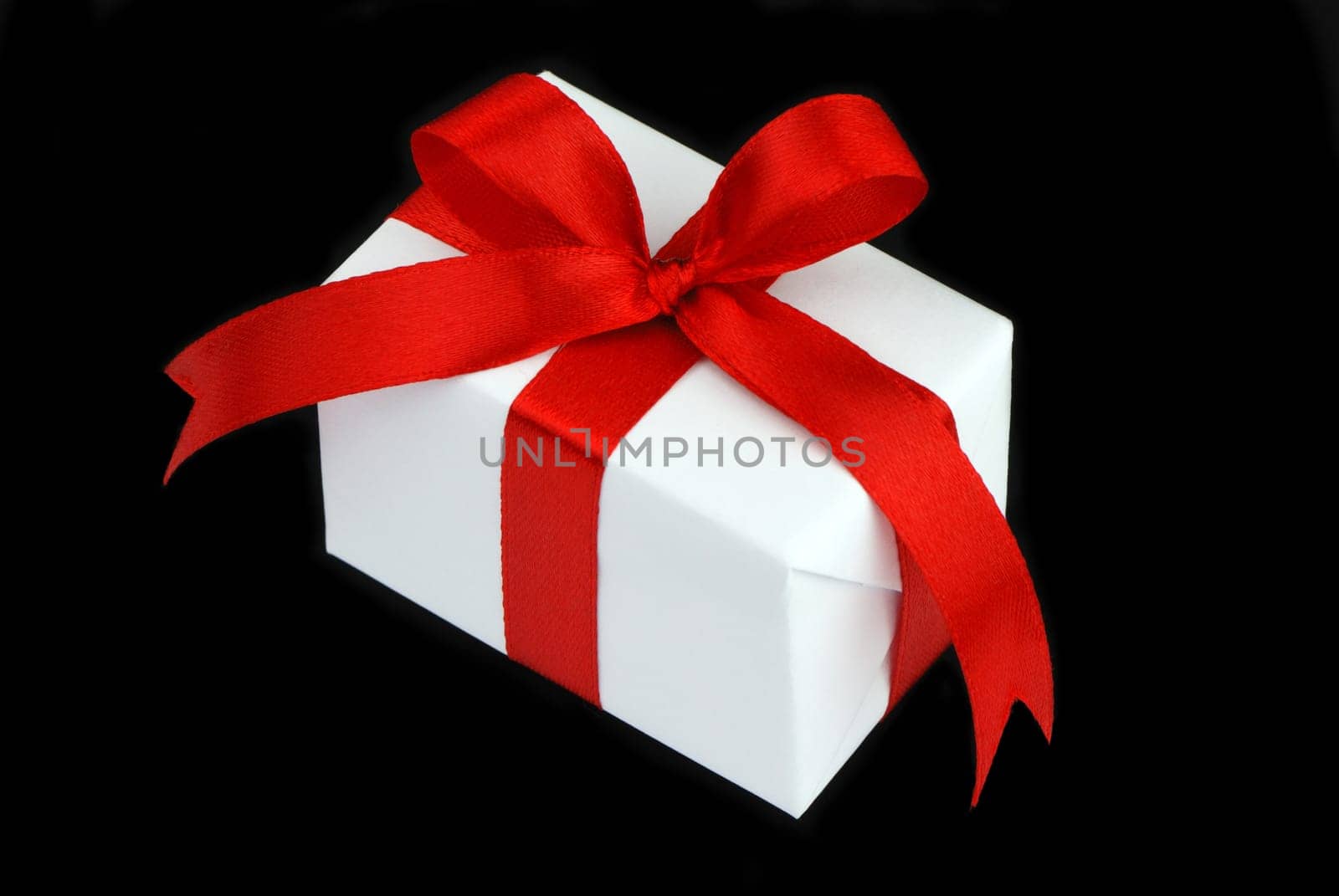 white gift box with red ribbon isolated on black background