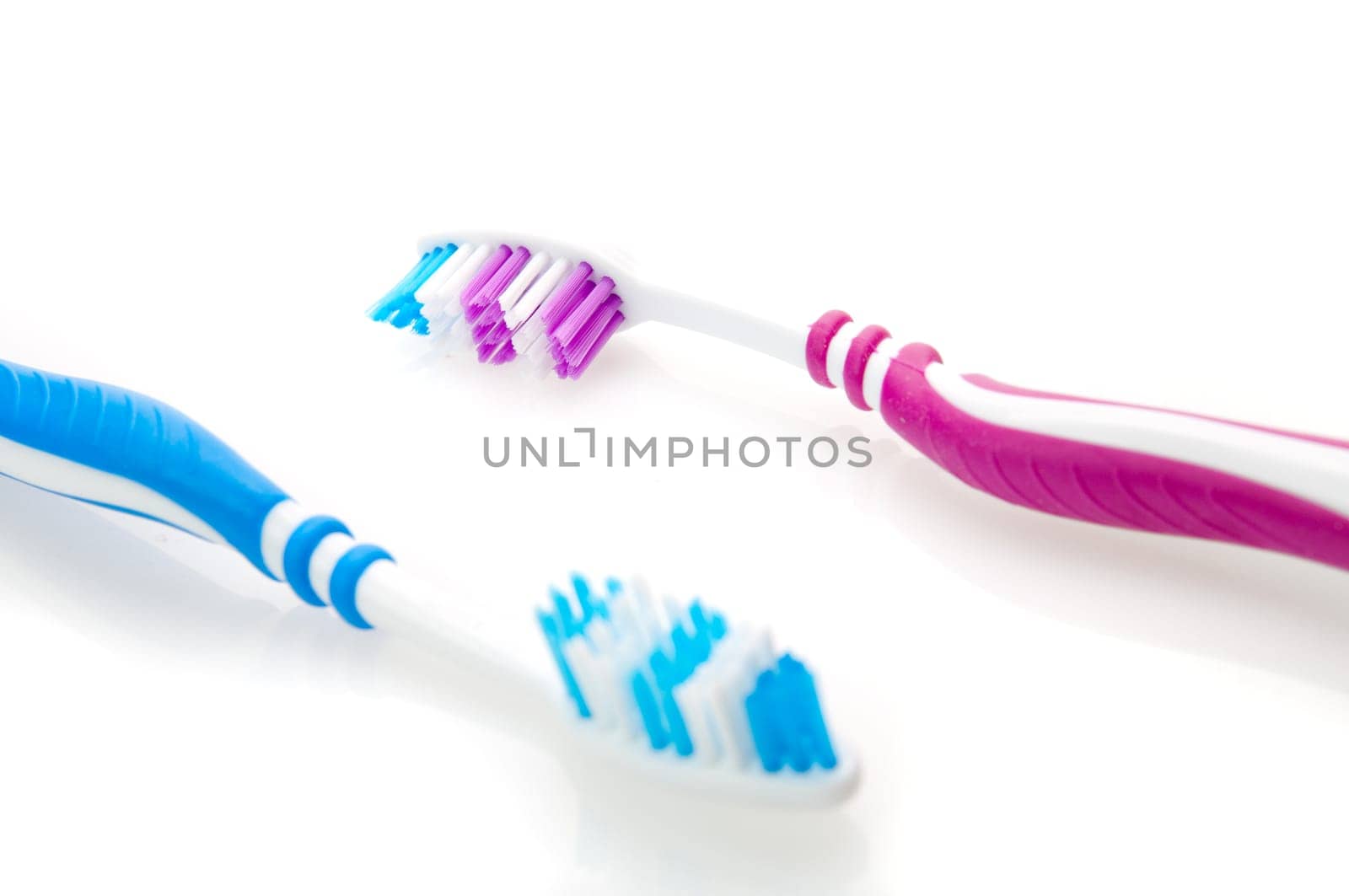 two color toothbrushes. Focused on reb toothbrush