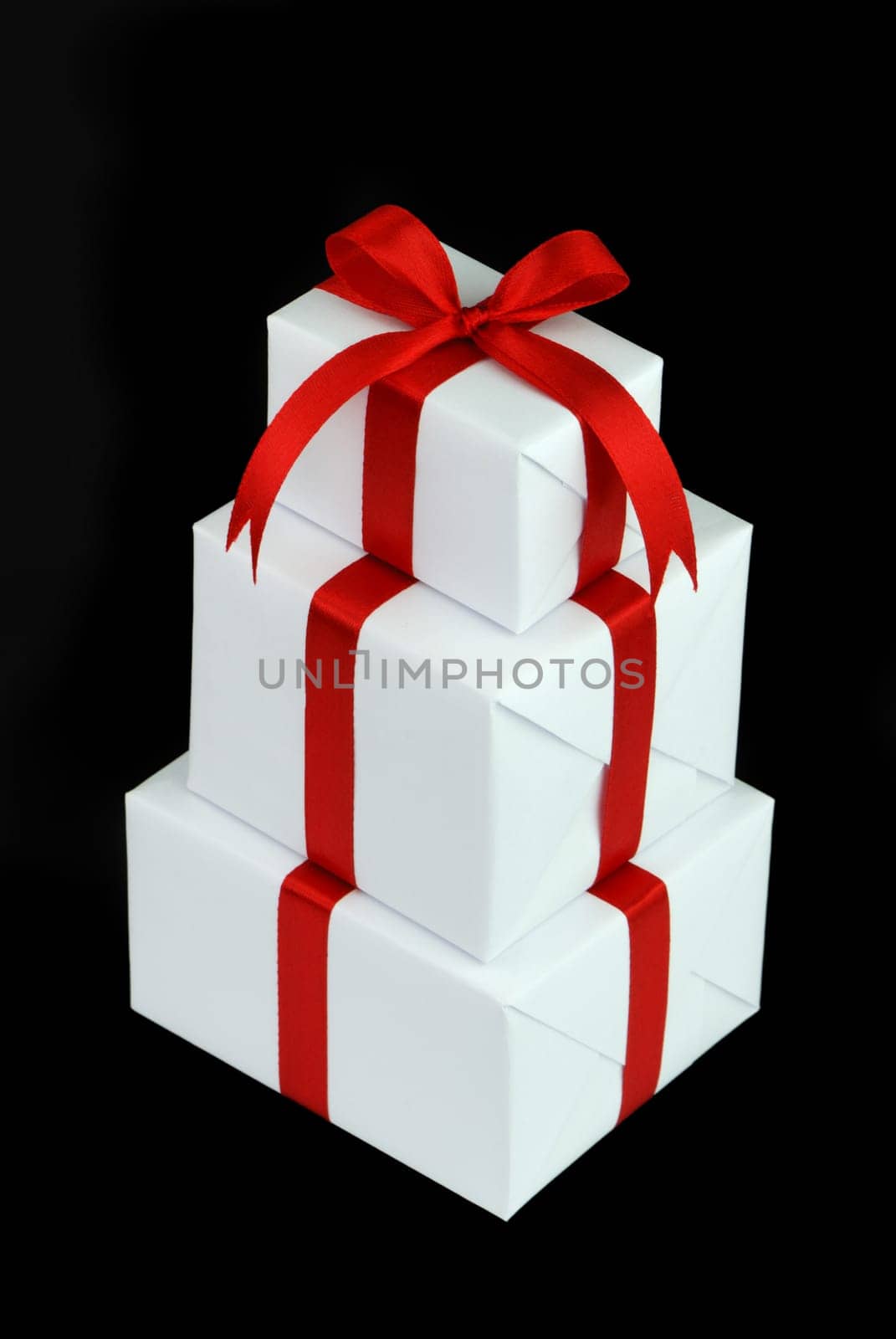 three white gift boxes with red ribbon isolated on black background