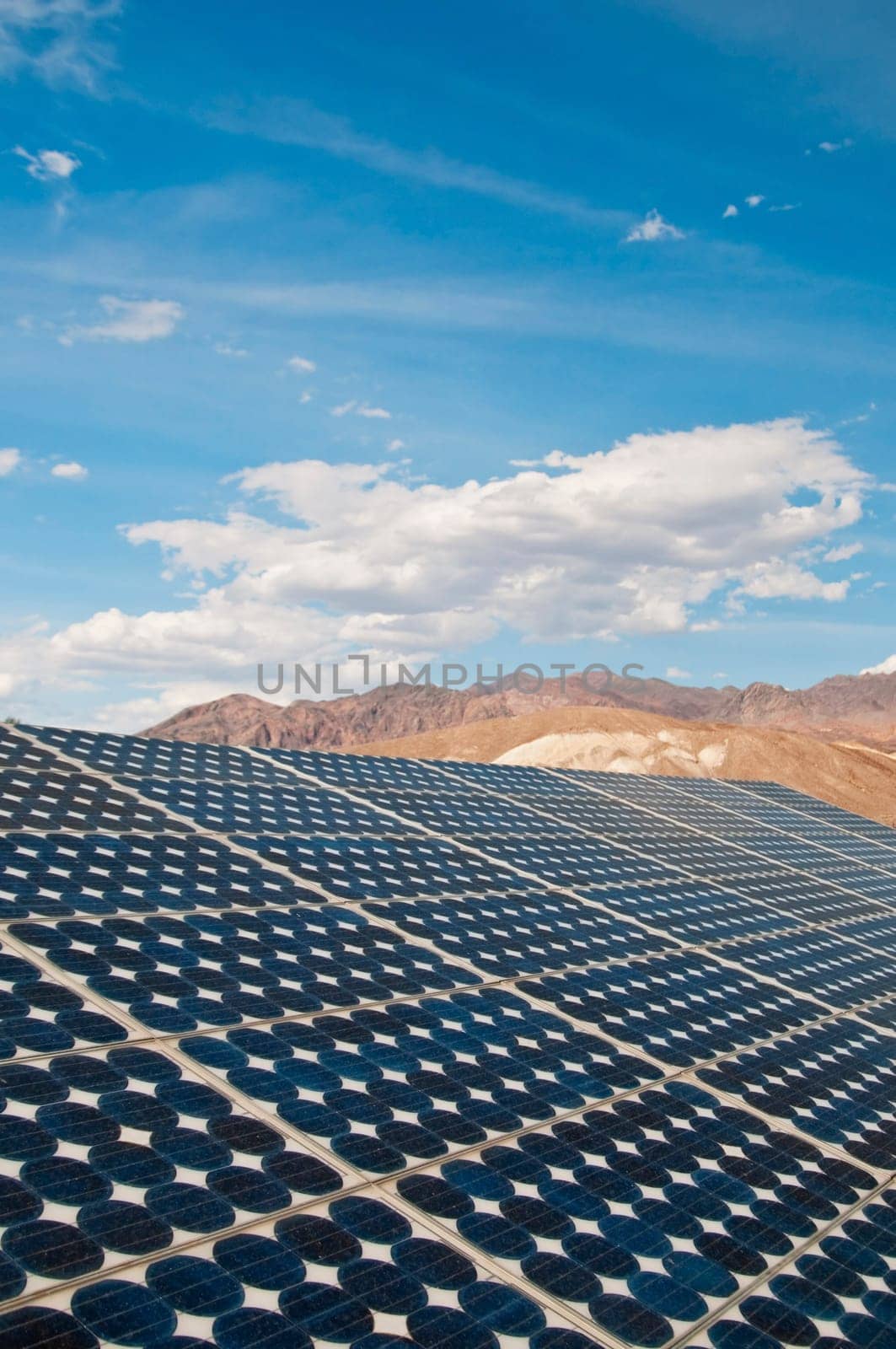 solar panel with blue sky, clouds, and mountains in the background