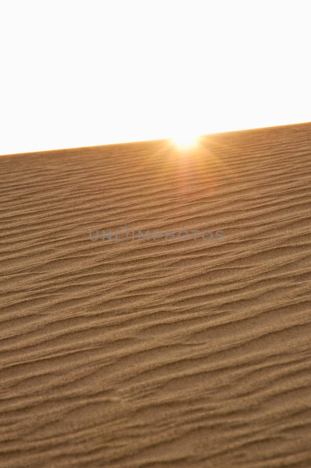 sun peaking over ridge of sand dune in Death Valley National Park, CA