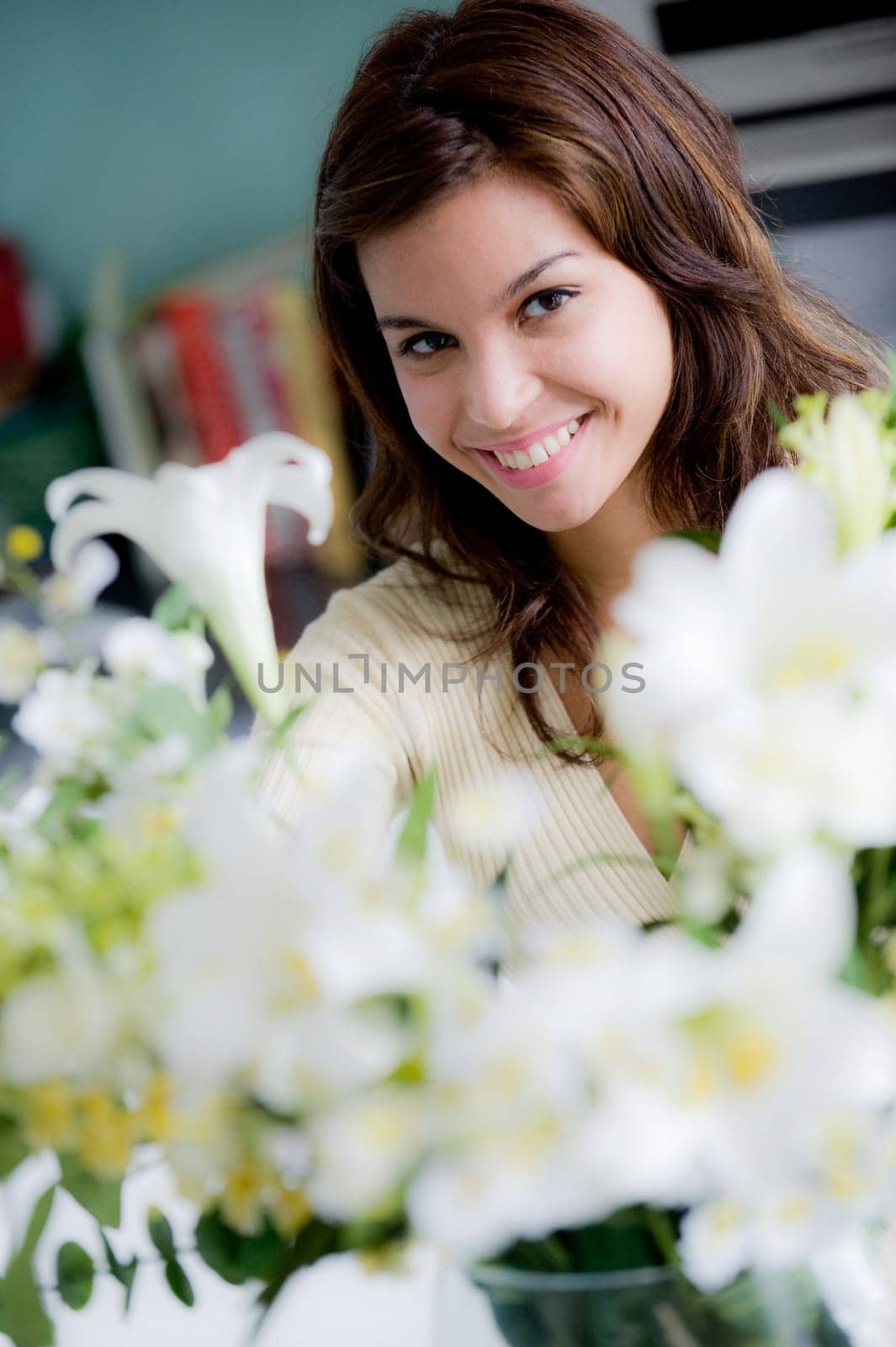 A pretty young woman arranging flowers in the kitchen