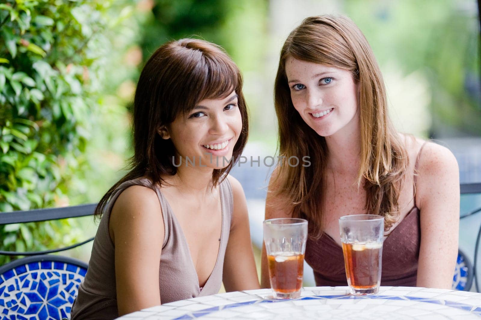 Two young attractive women having iced tea outside