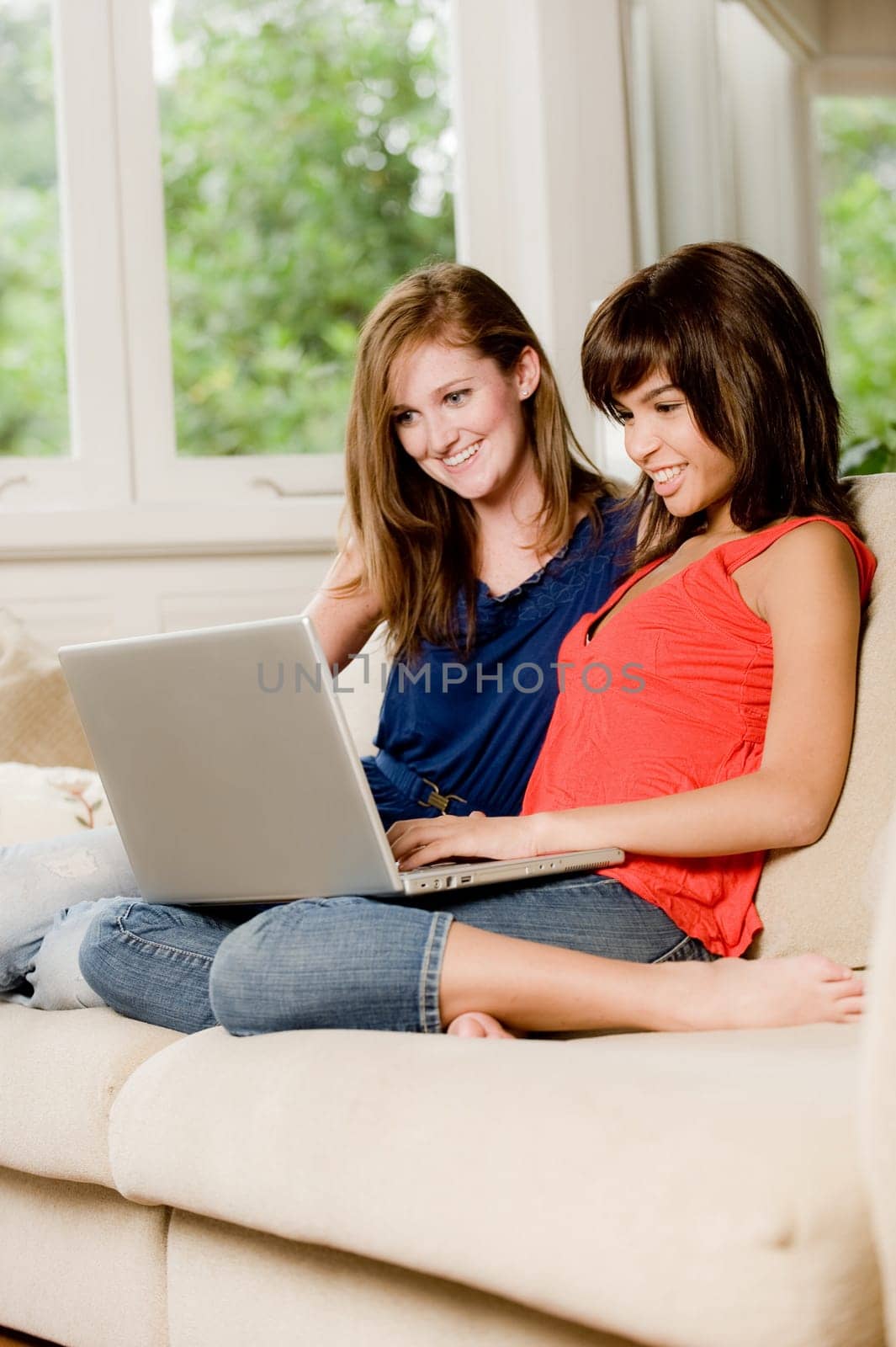 Two young woman at home on the sofa with laptop