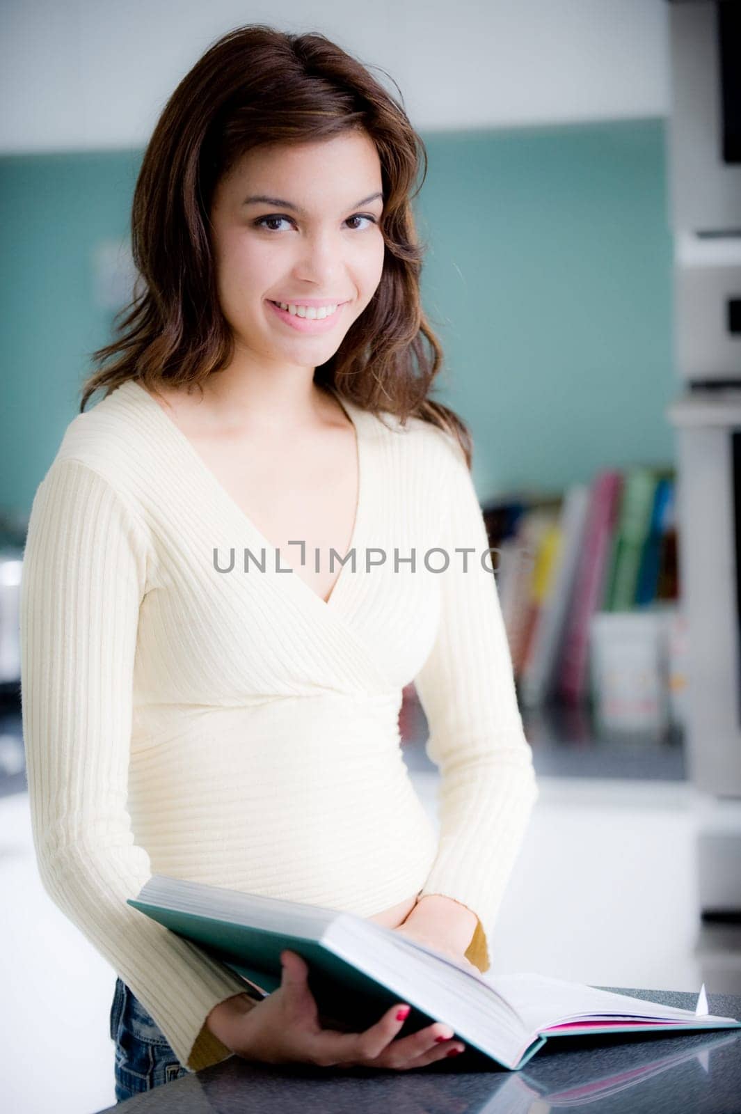 A young woman reading a cookery book in the kitchen