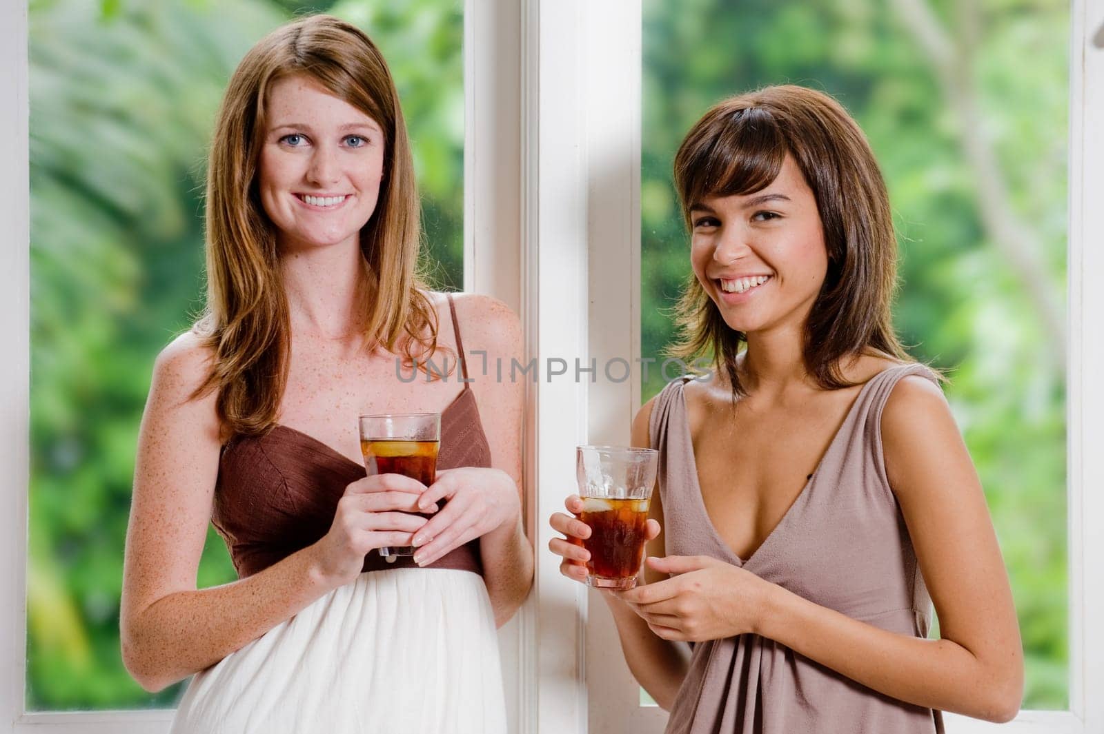 Two women standing together with glasses of ice tea
