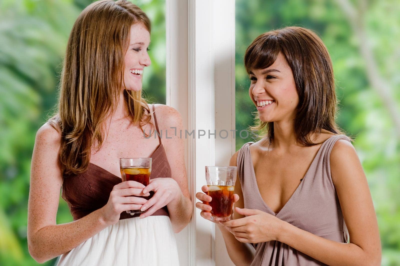 Two women standing together with glasses of ice tea