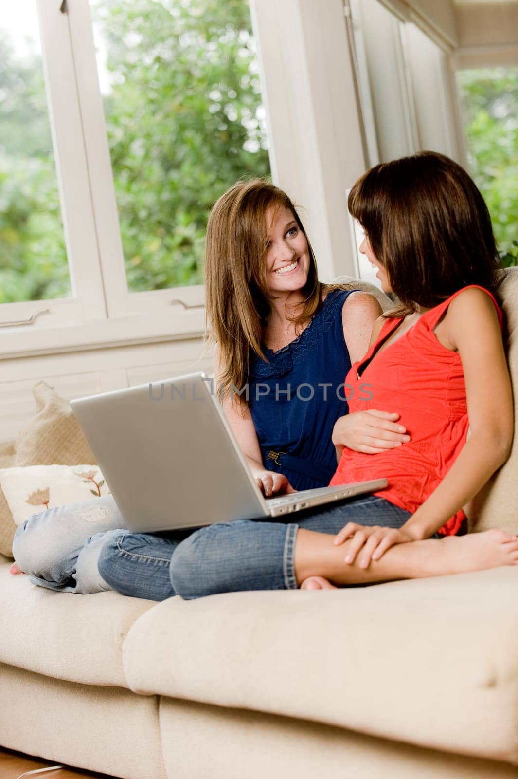 Two young woman at home on the sofa with laptop