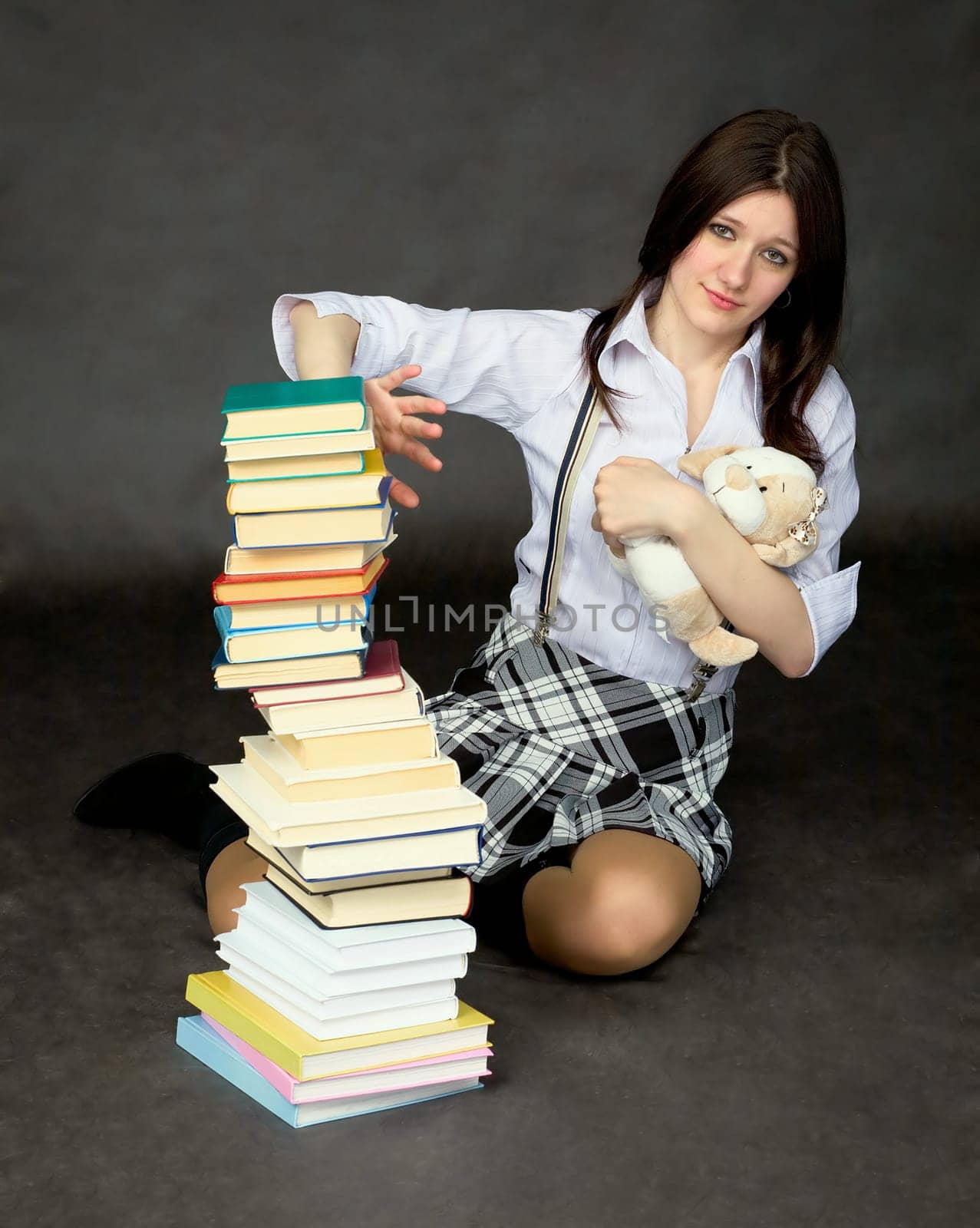 Schoolgirl with the big pile of books and toy dog