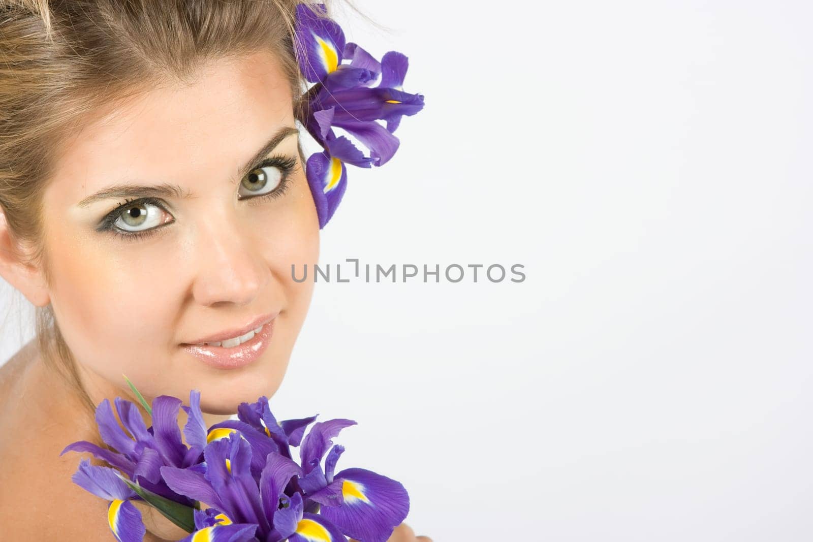 Close-up fresh funny blonde with beautiful make-up with iris flowers