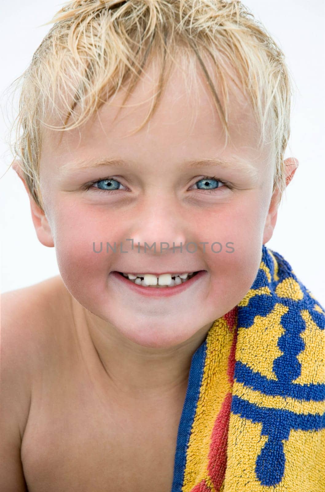A beautiful blue eyed blonde 8 year old boy is happily smiling for the camera during a day at the beach.