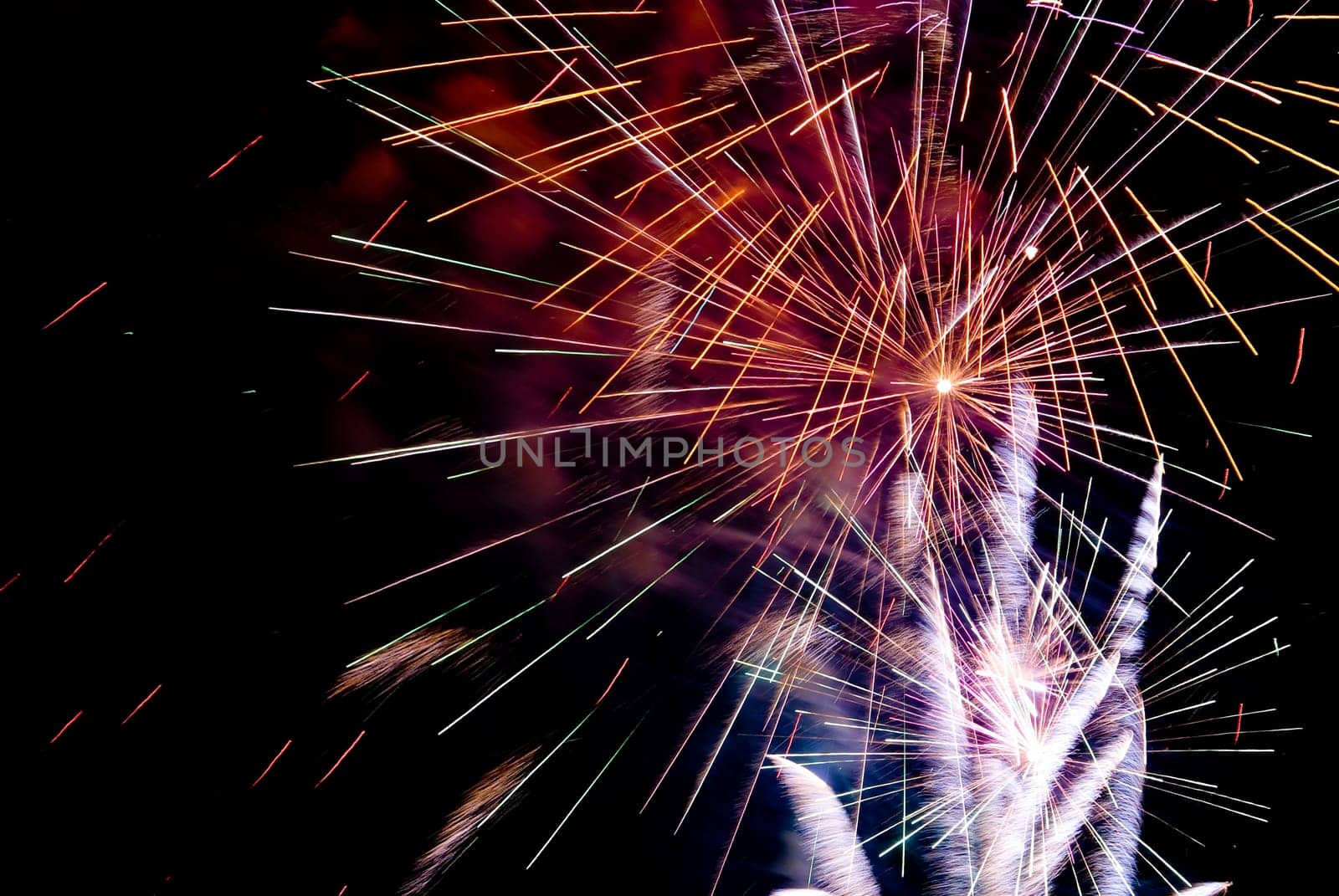 Fireworks exploding in the dark of the evening sky.