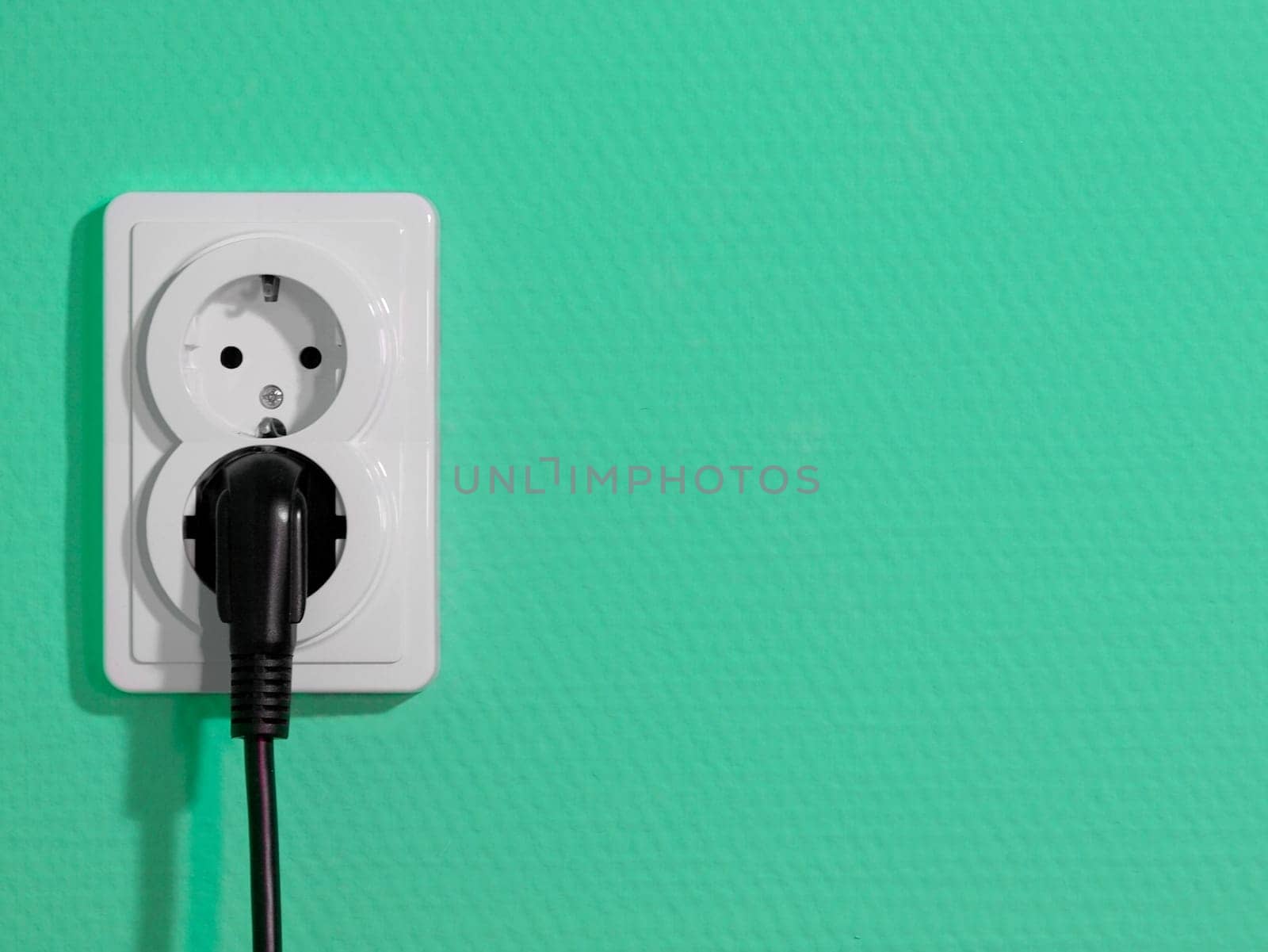 White electric socket on green wall