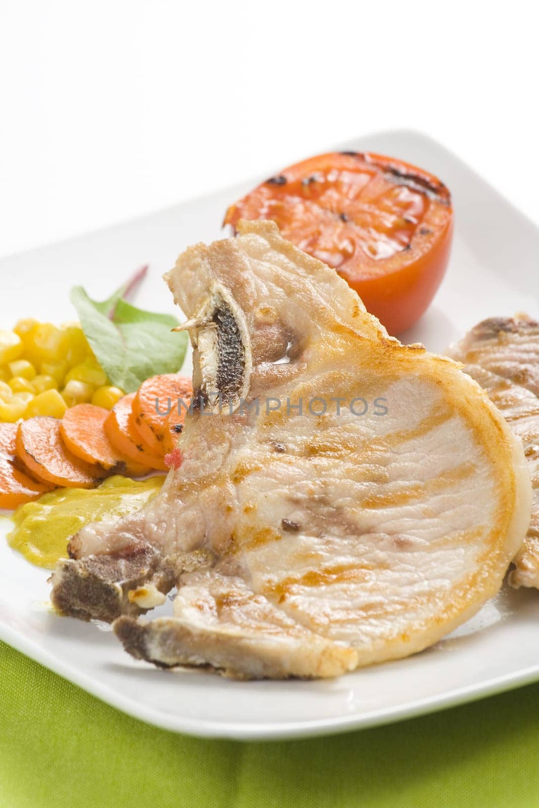 tasty pork chop with corn carrot tomato isolated
