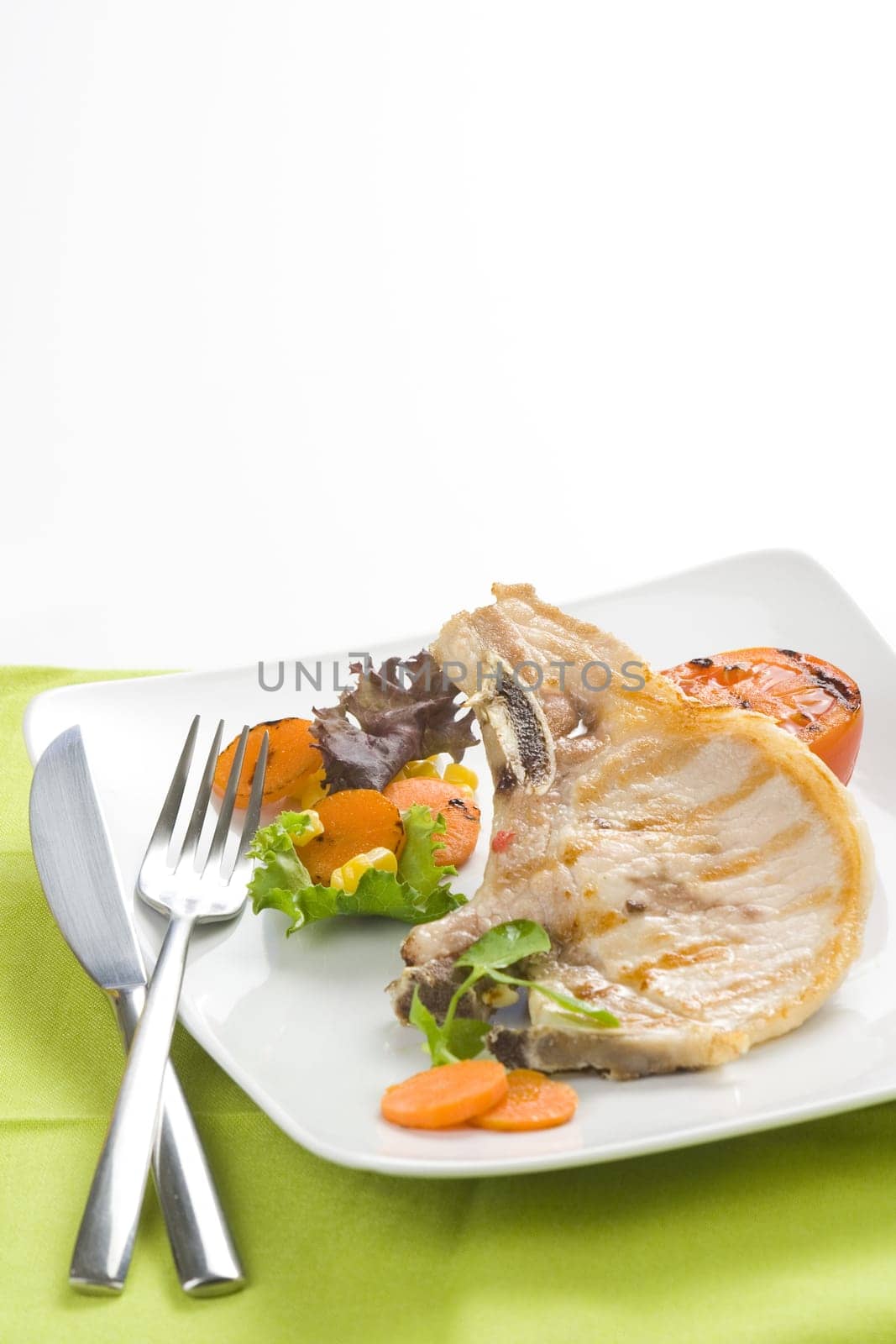 tasty pork chop with corn carrot tomato isolated