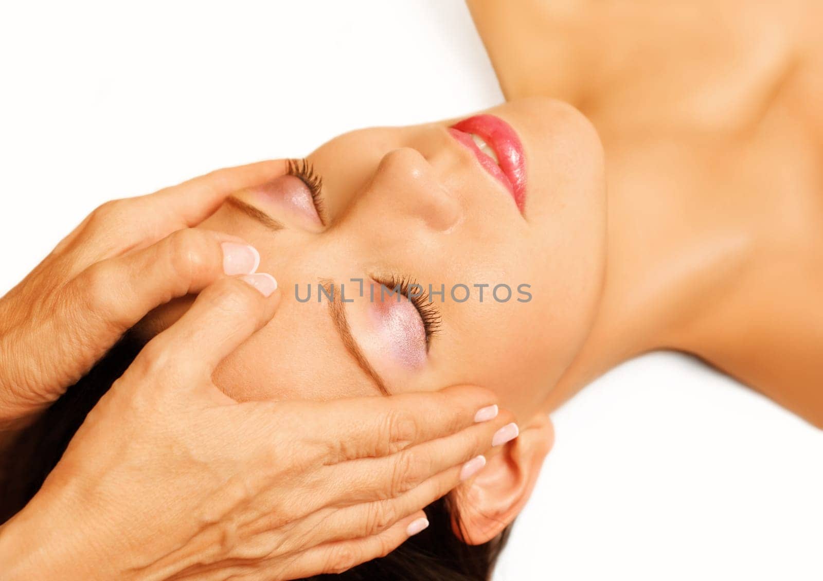 Young woman lying on her back, gets massage,reiki,acupressure on her head, focus on face and hands