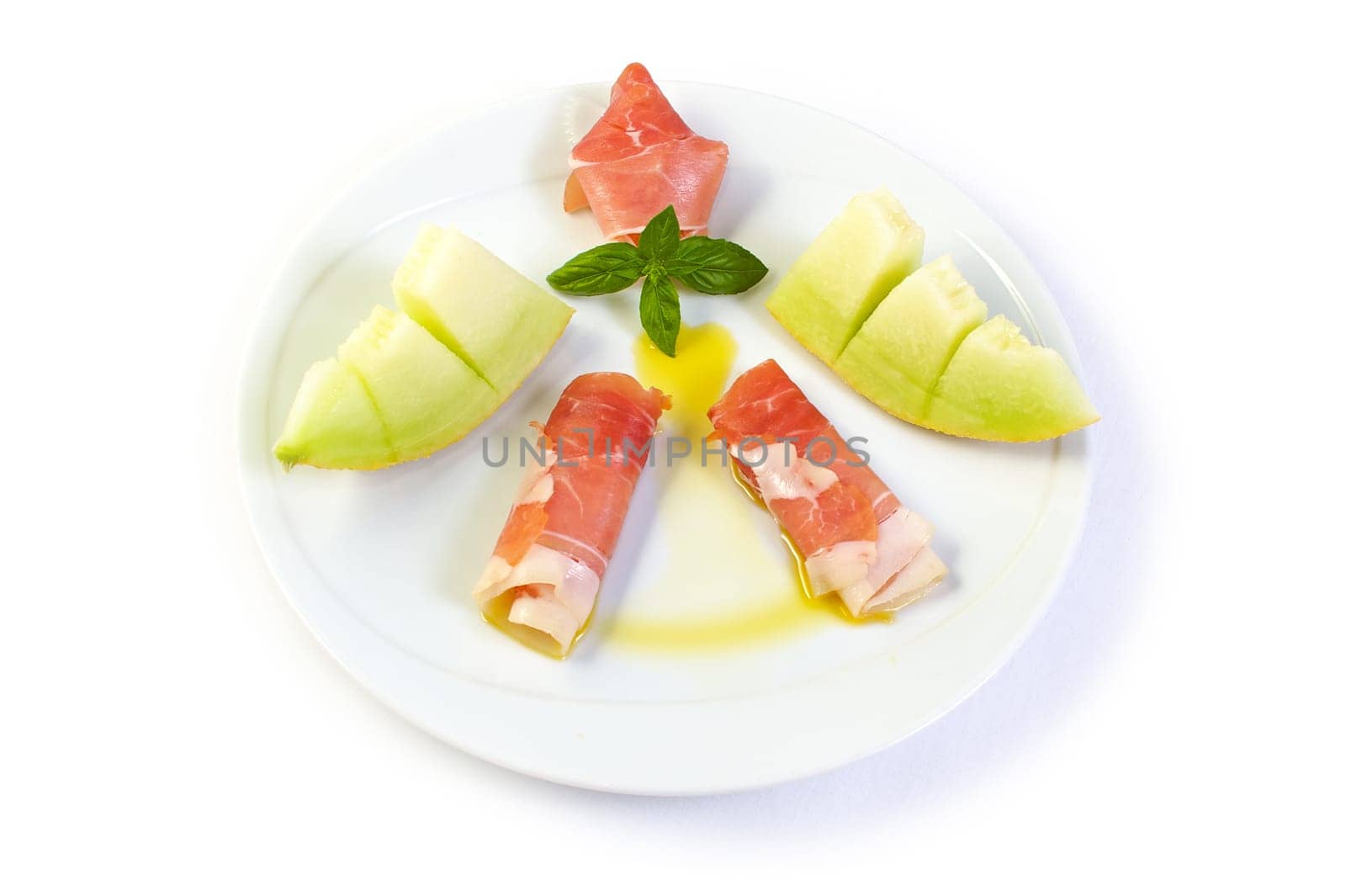 A dish with raw ham, yellow melon and olive oil