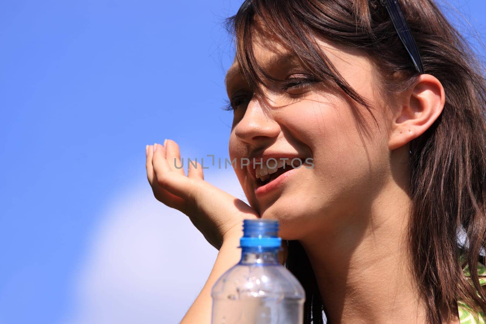 Girl drinking water against blue sky in sunny day