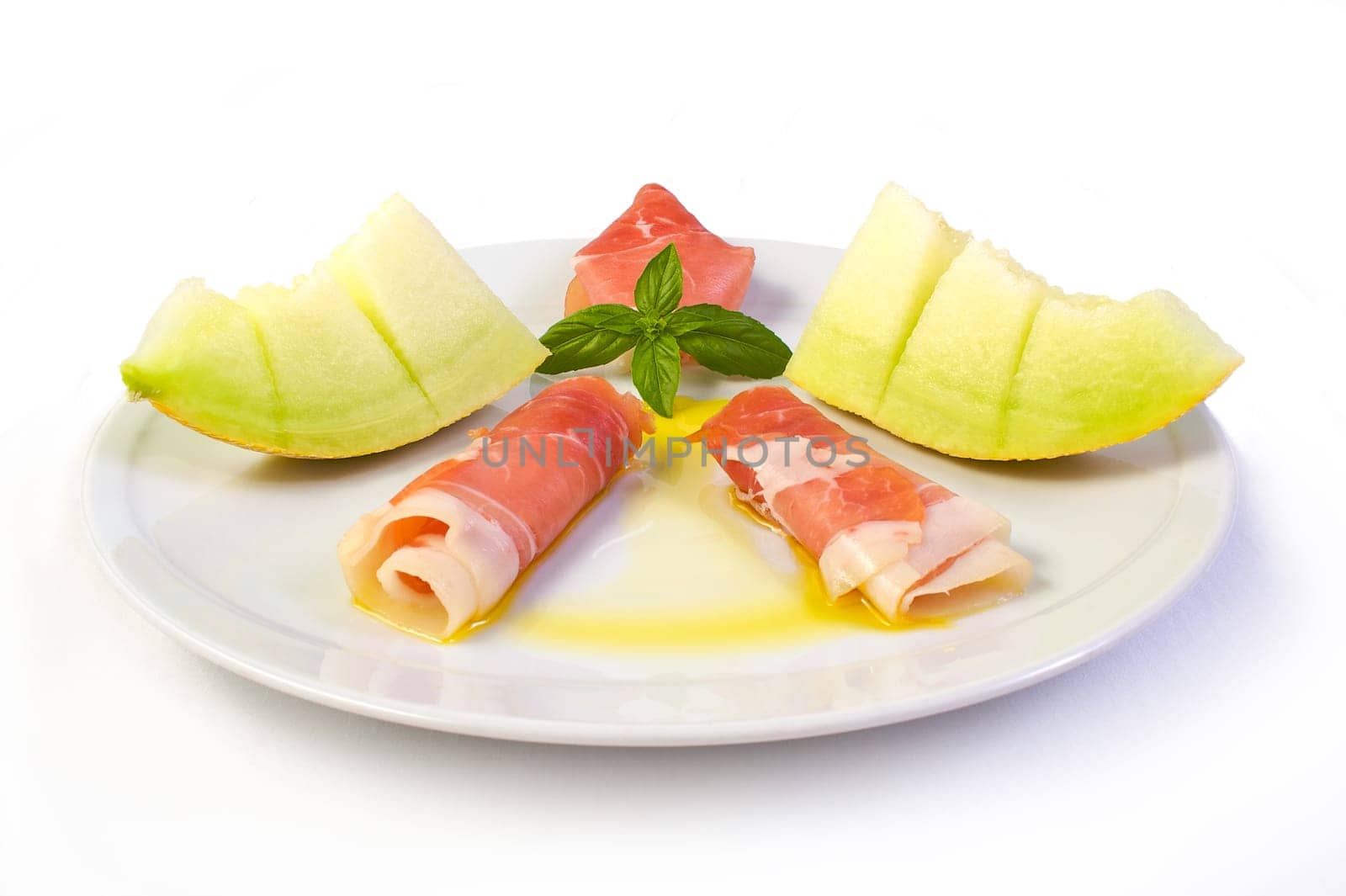 A dish with raw ham, yellow melon and olive oil