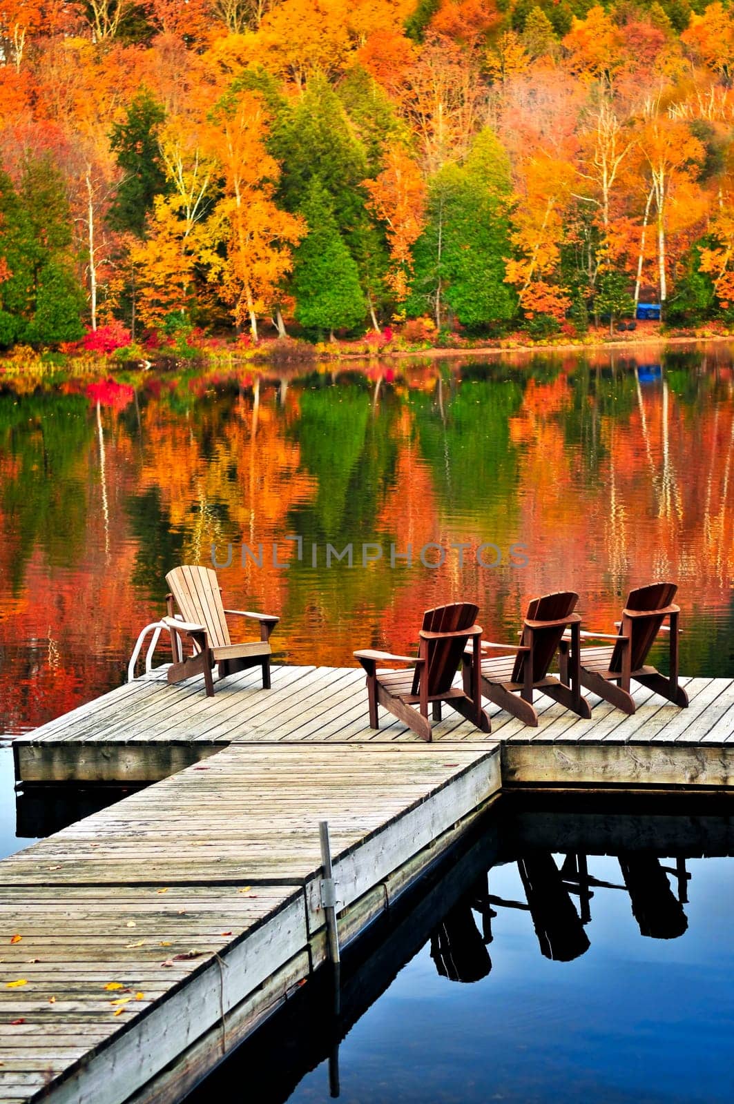 Wooden dock with chairs on calm fall lake