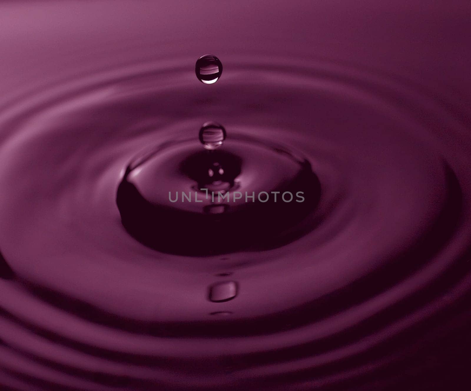drops of water going into a bigger pool of water that is purple